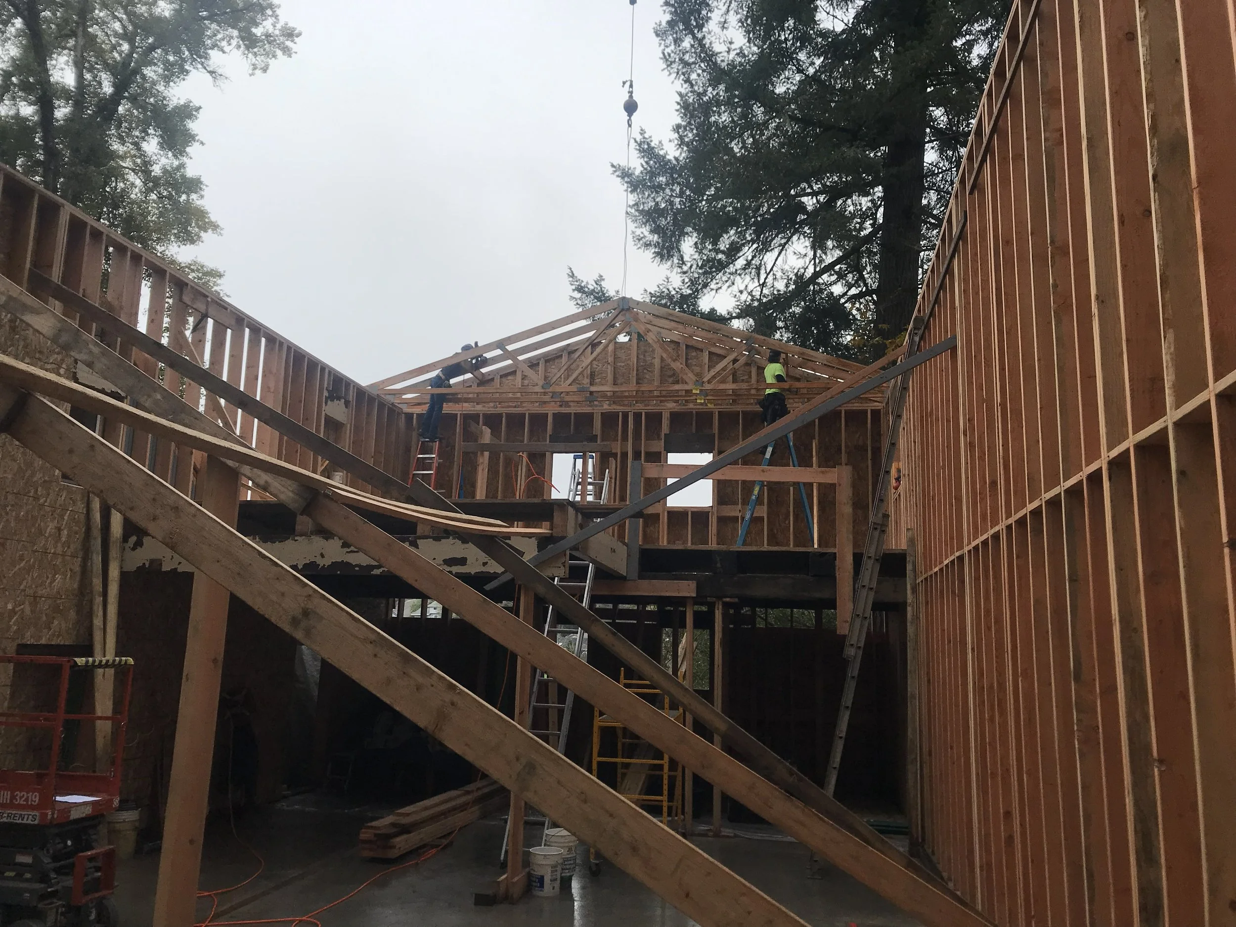 Construction site where workers are building a wooden house frame, with ladders and scaffolding in place. veteran owned residential general contractor Roseburg OR