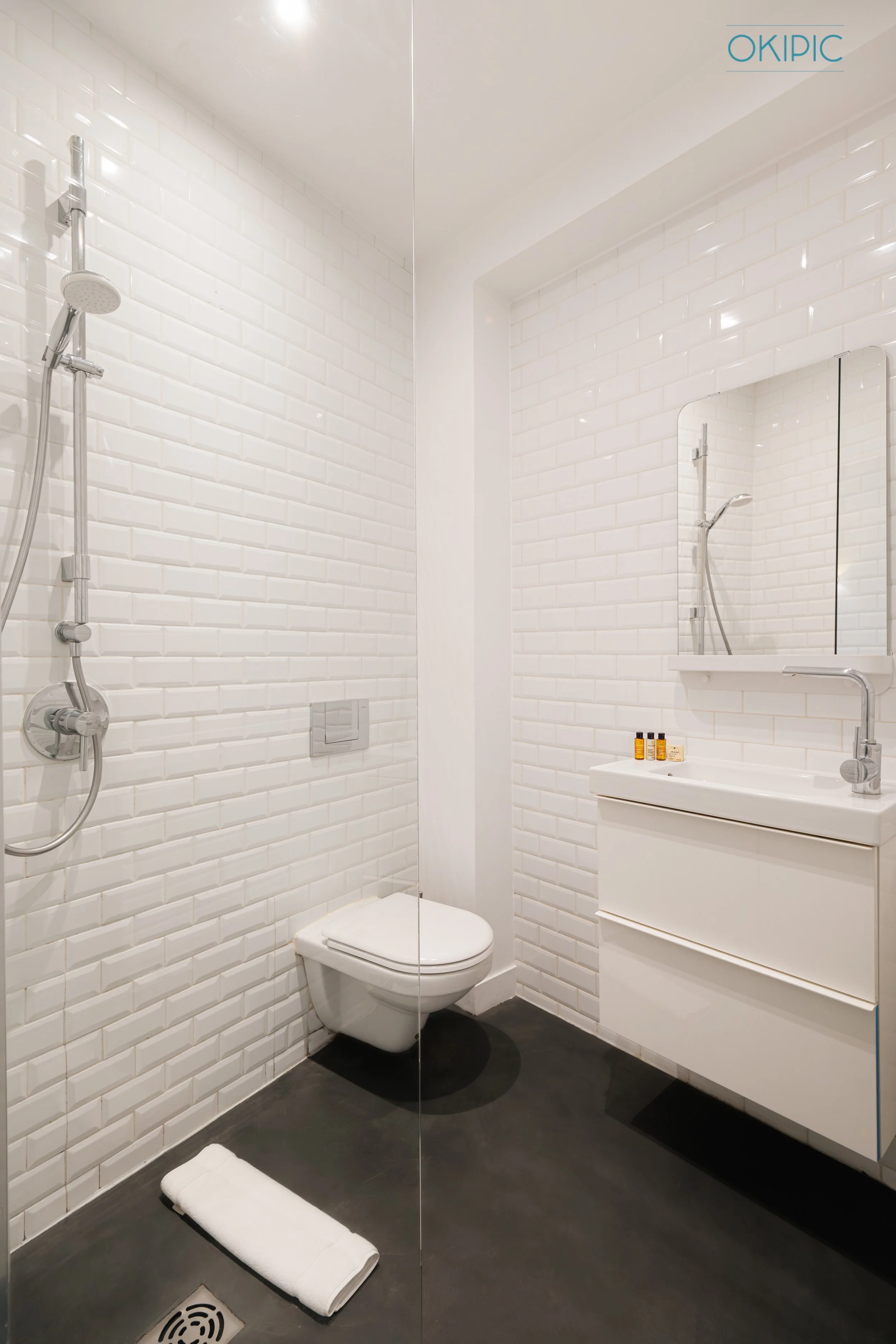 Modern, bright bathroom (1) with walk‑in shower, wall‑hung toilet, and floating vanity.