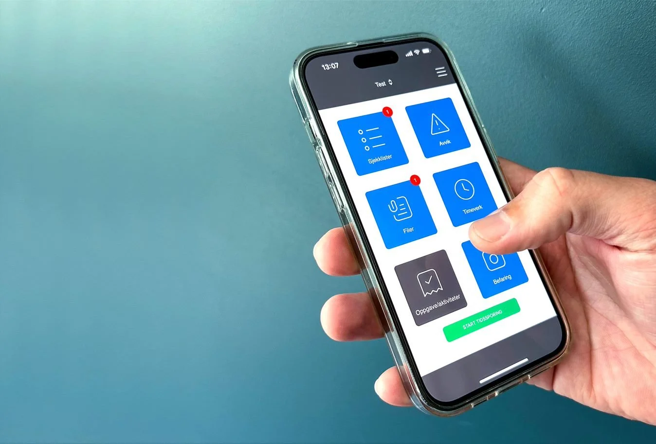 En person holder en smarttelefon med en app åpen, som viser ikoner for sjekklister, avvik, filer, tidsur, oppgaveaktiviteter og betaling.