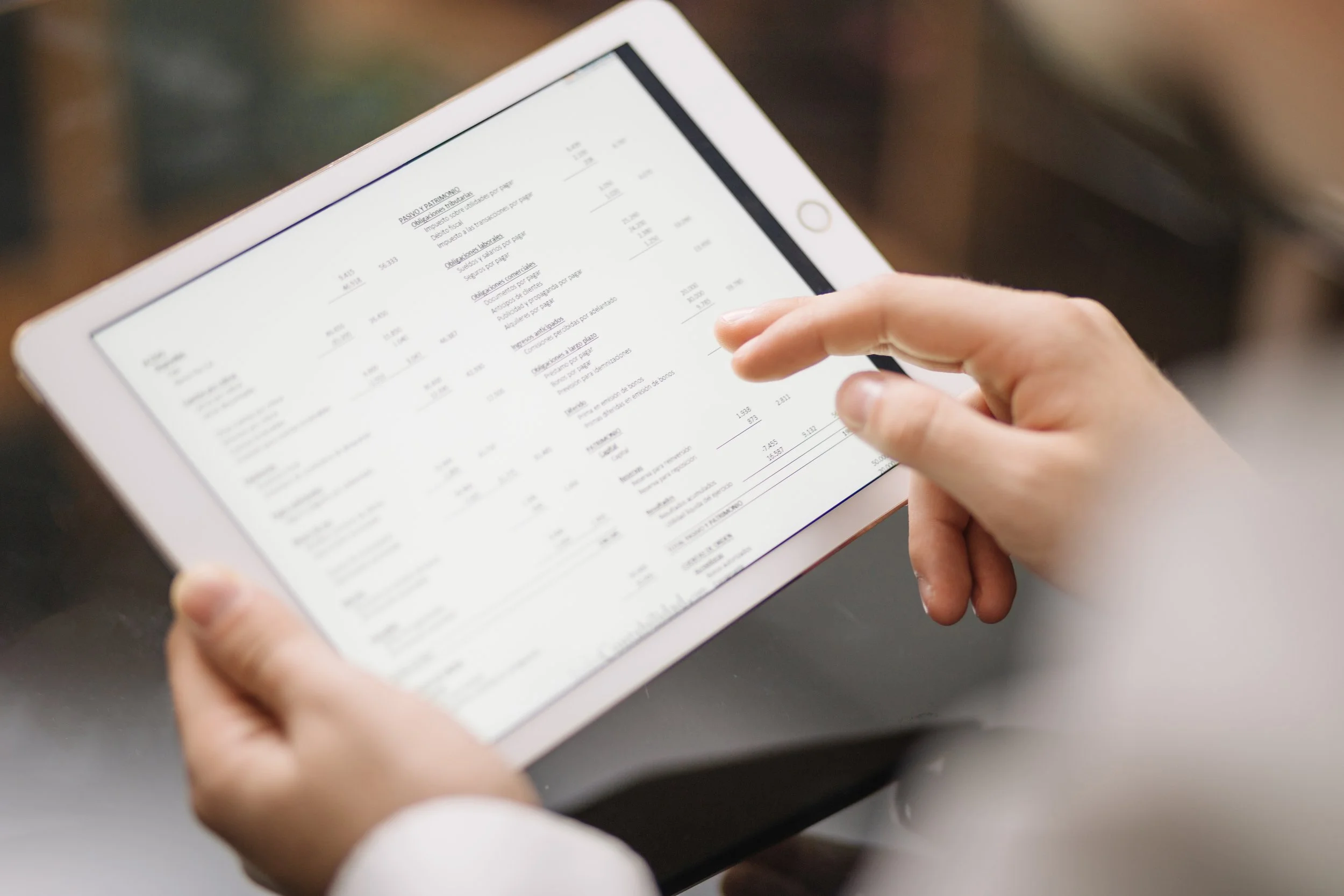 Person som holder en nettbrett og ser på en digital regning eller kvittering.