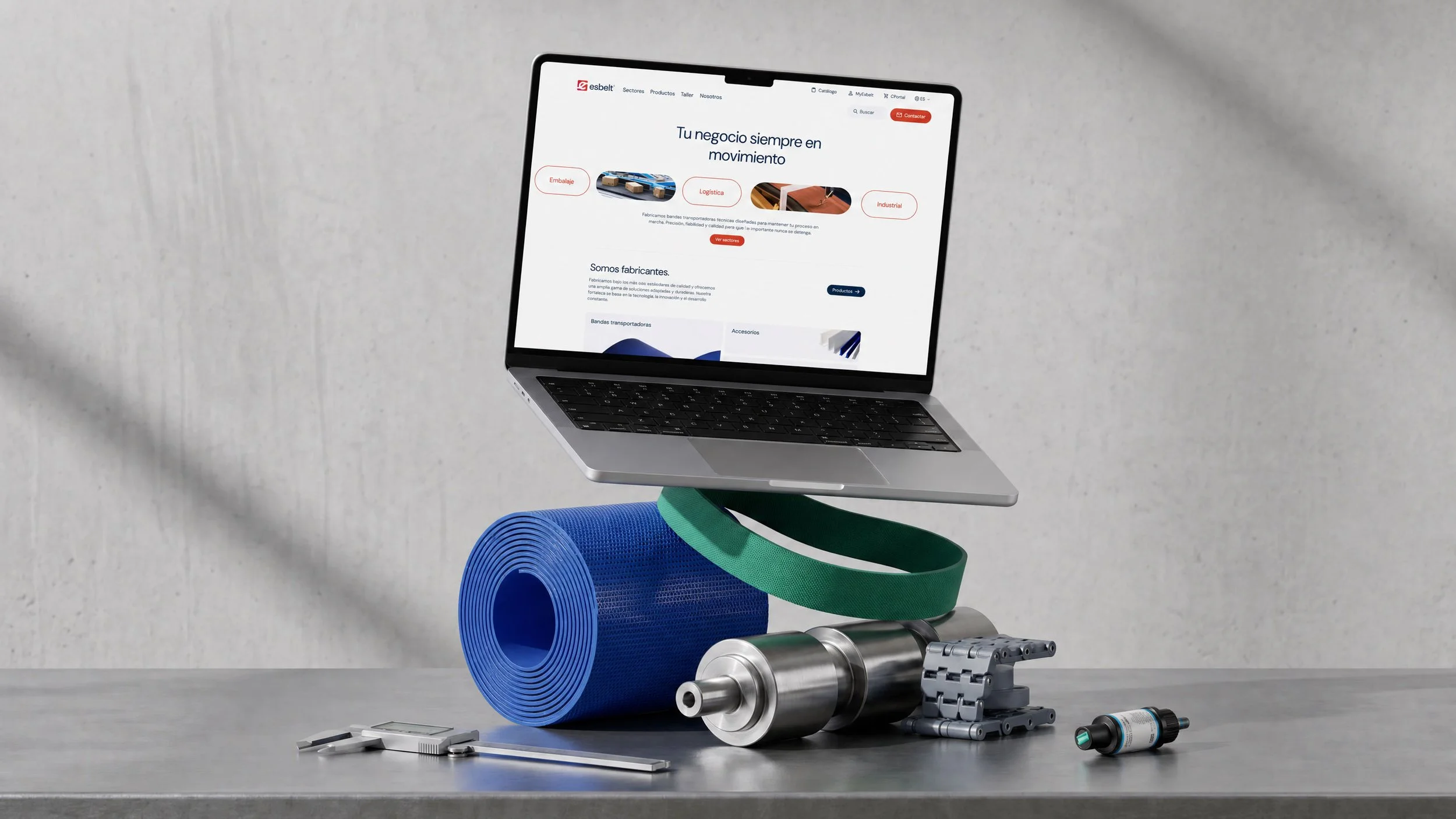 Portátil flotando sobre componentes industriales como rodillos, correas y piezas mecánicas, mostrando la web de Esbelt con soluciones para distintos sectores.