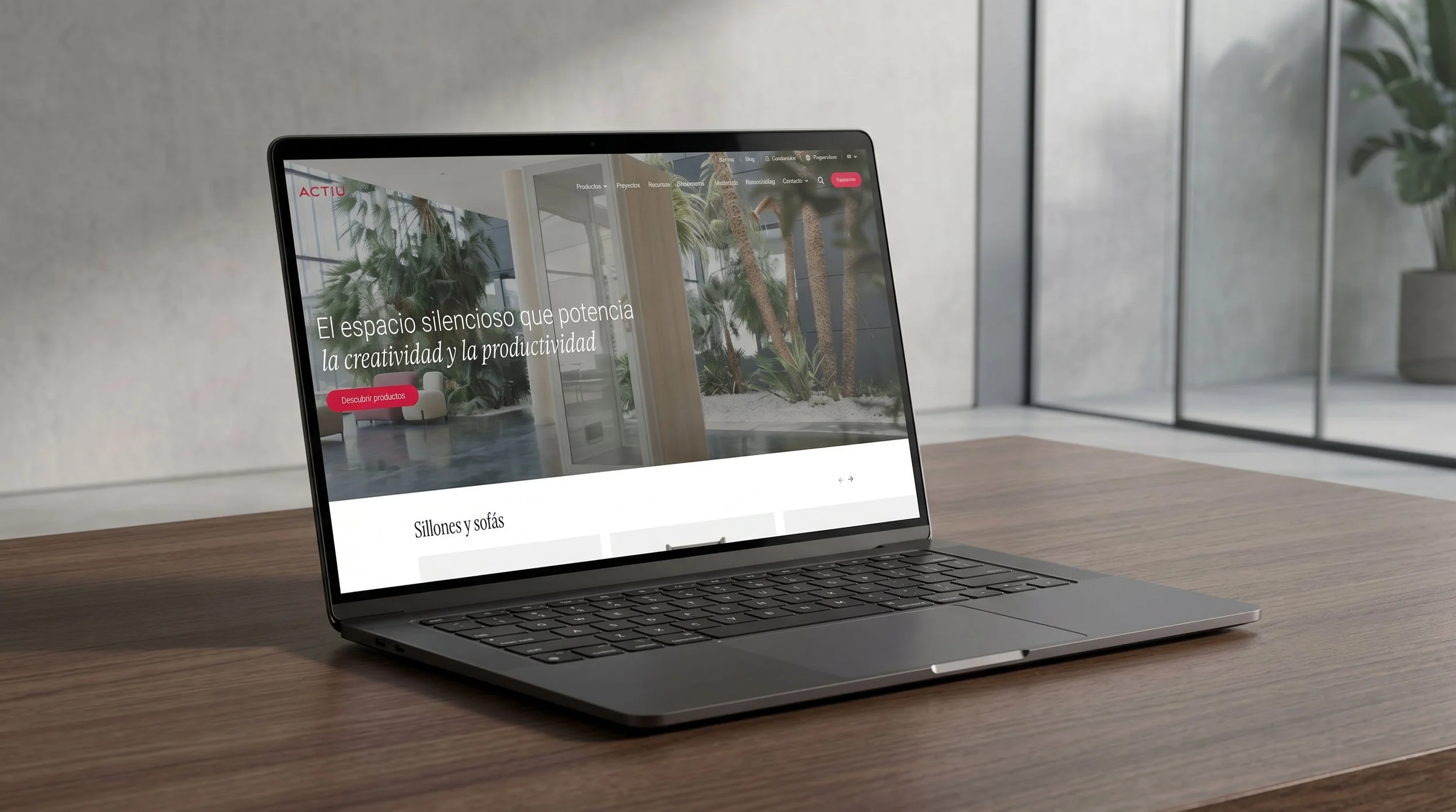 Ordenador portátil sobre escritorio mostrando la web de Actiu, con portada sobre mobiliario de oficina y mensaje sobre creatividad y productividad.