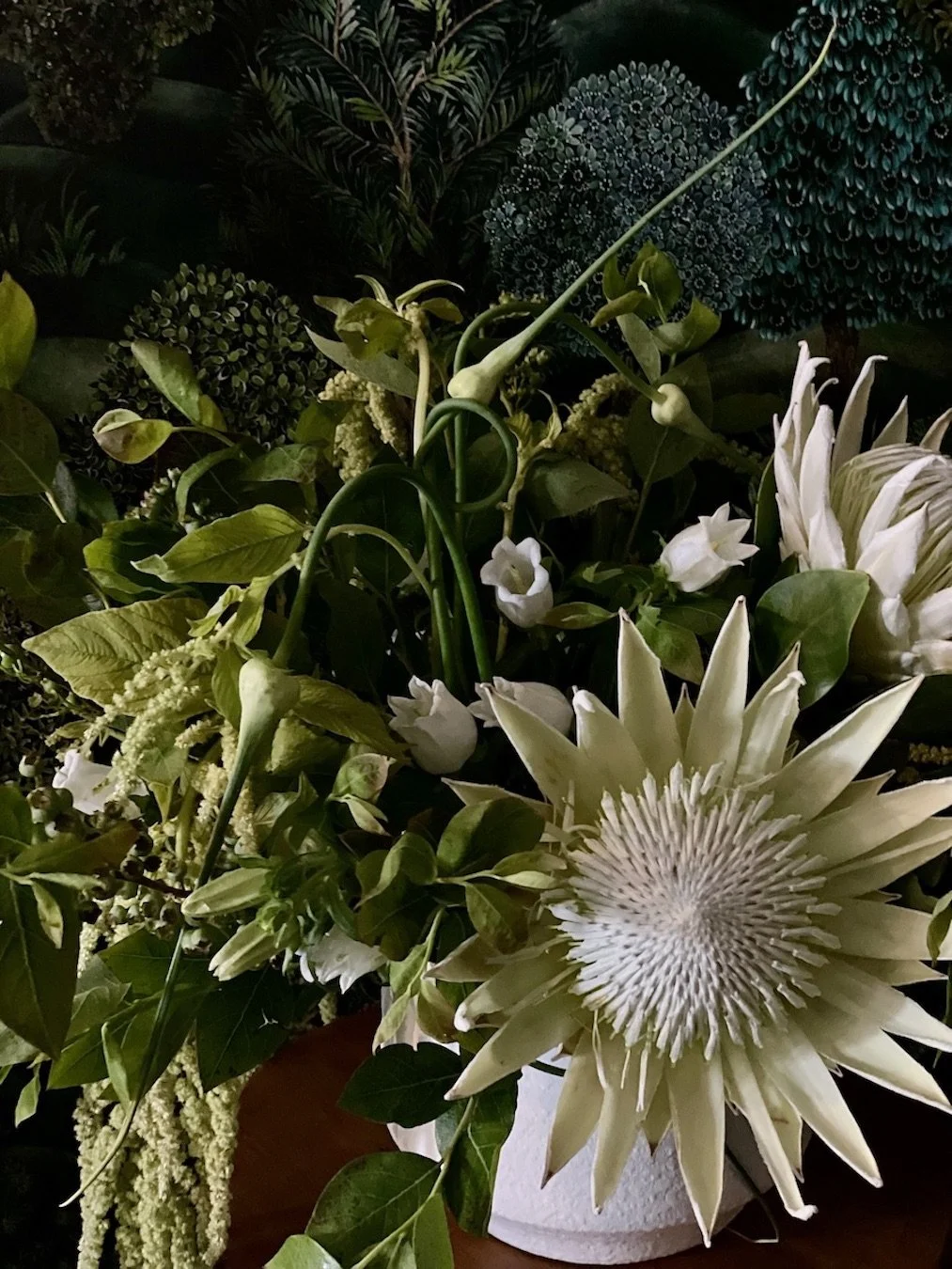 A bouquet of white flowers, including a large passionflower, surrounded by various green leaves and foliage.