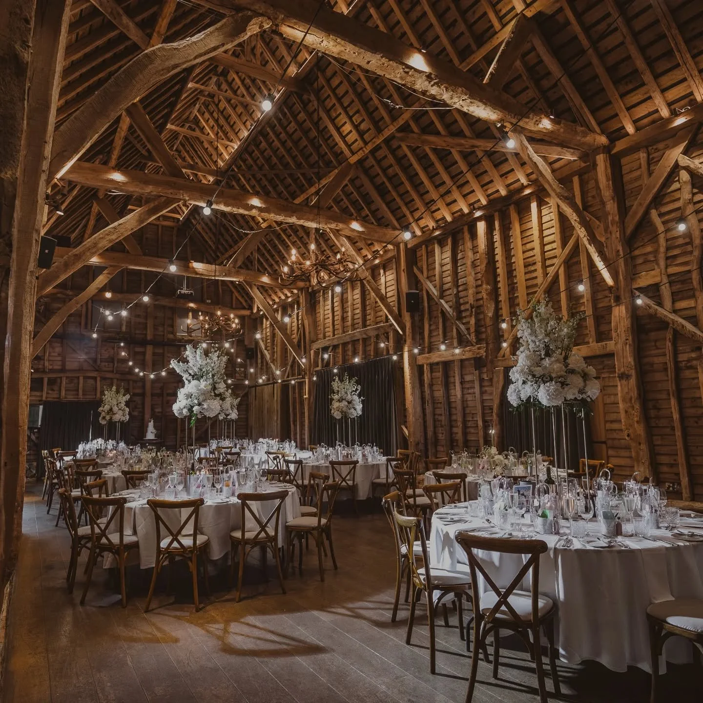 Tall statement table arrangements in the stunning barn at Redcoats. Bold hydrangeas, roses &amp; lush delphiniums for added  height. Really versatile designs that can be used during the ceremony &amp; then moved onto the tables. Use with a mix of low