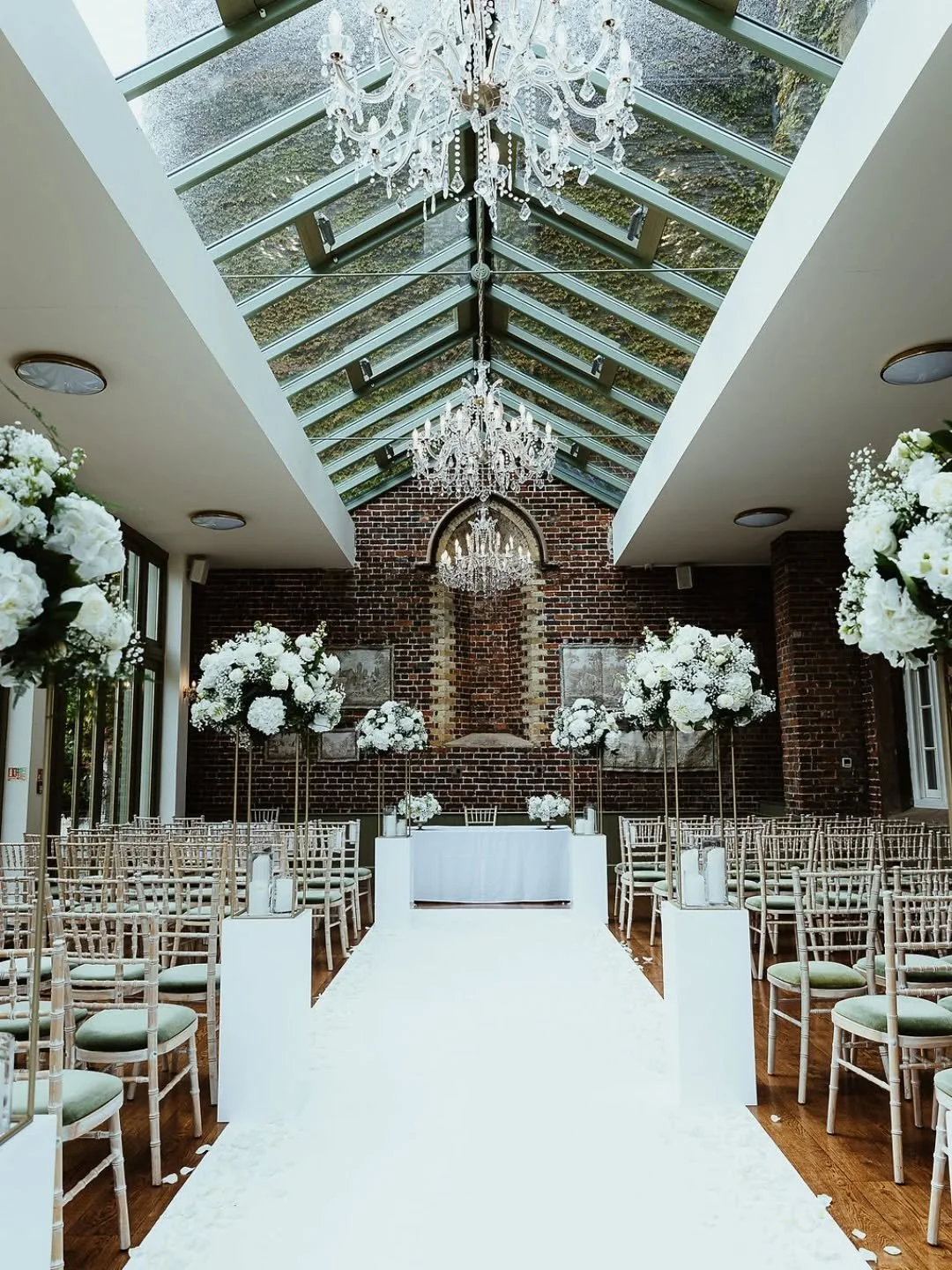 The conservatory at Offley Place,  all set for a beautiful wedding ceremony. Using tall table arrangements on plinths to line the aisle. 🤍 The perfect all white set up. 

Venue @offleyplace 
Photo @shrigleyphotographyfilm 

#hertfordshireflorist #be