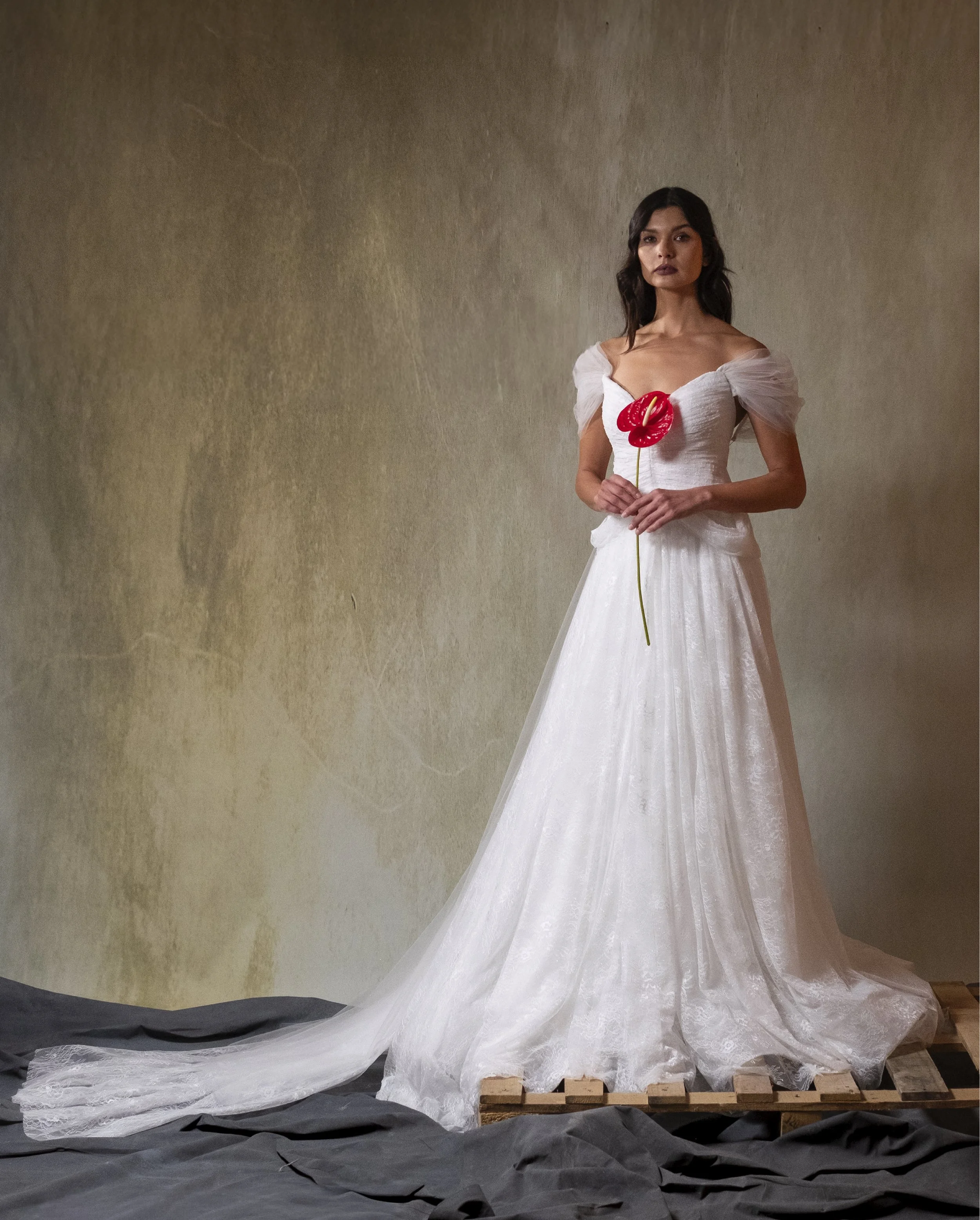 Hand-Draped chantilly lace gown featuring low hip points and soft hip drape, paired with tulle cape with long train and off-the-shoulder sleeves.