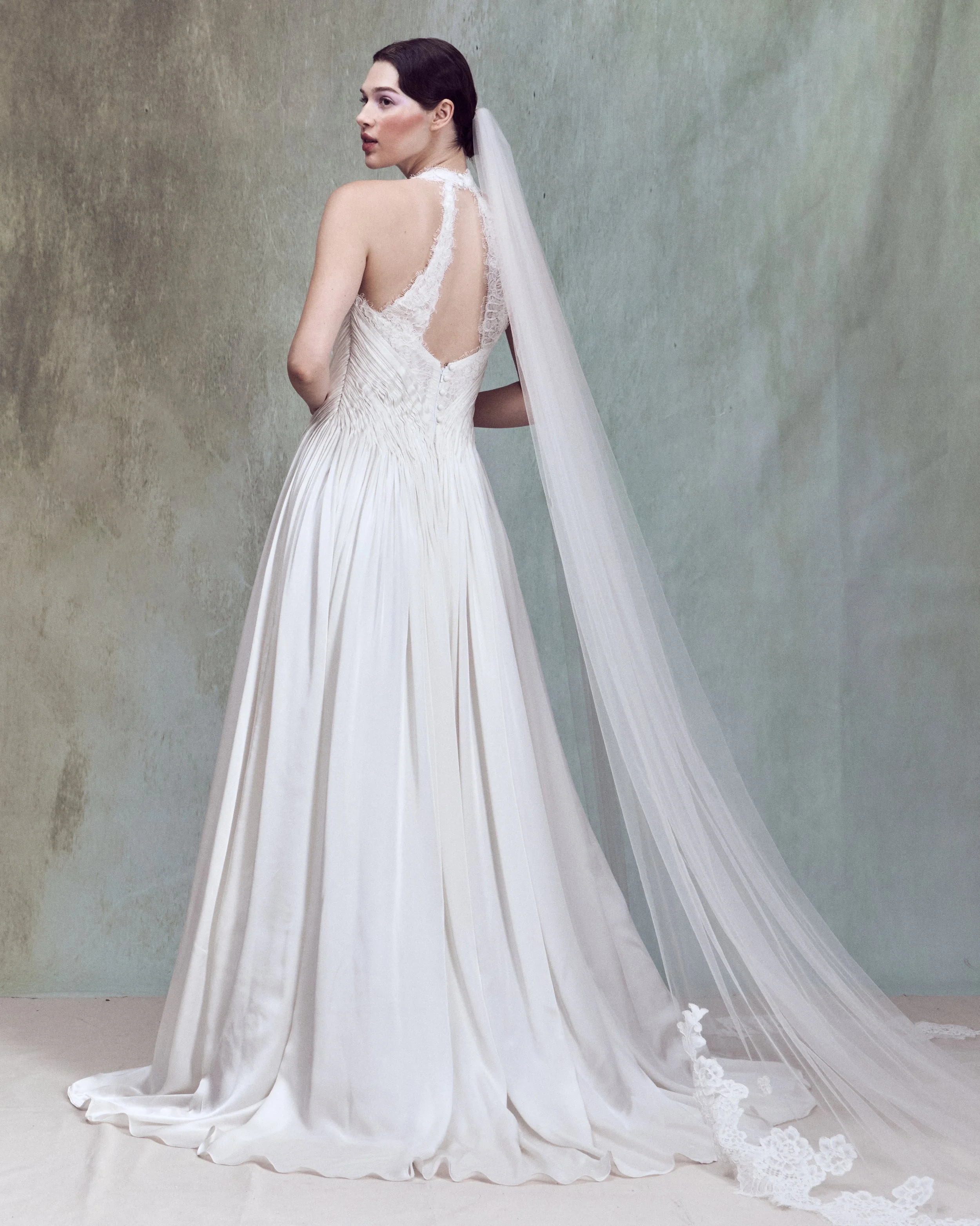 Corded lace applique gown with V-neckline halter bustier and hand-draped silk satin chiffon detail wrapping around the waist. 