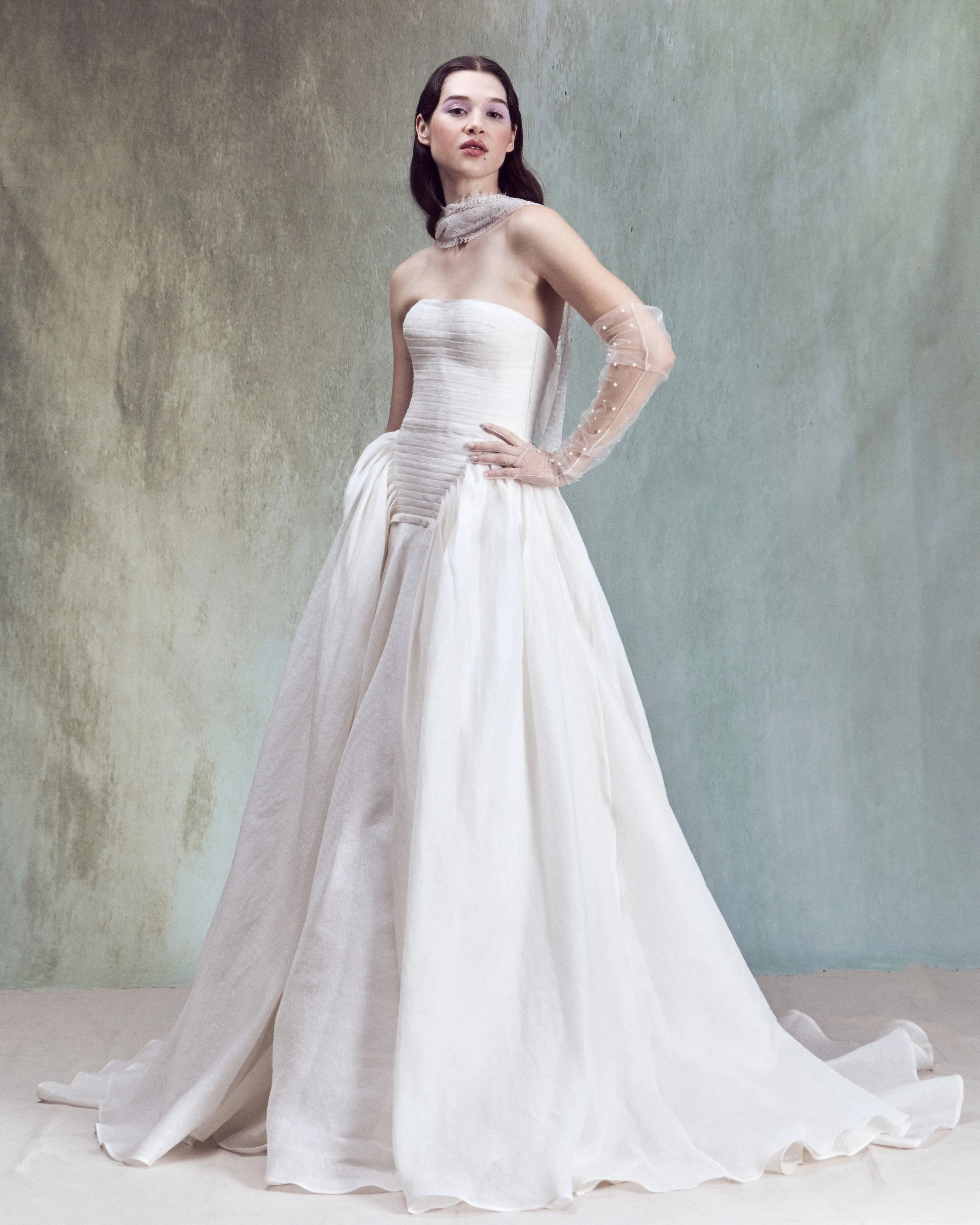 Strapless Silk Linen ball gown with a drop-waist bustier, horizontal hand-pleated draping, and full skirt with exaggerated volume at the sides.