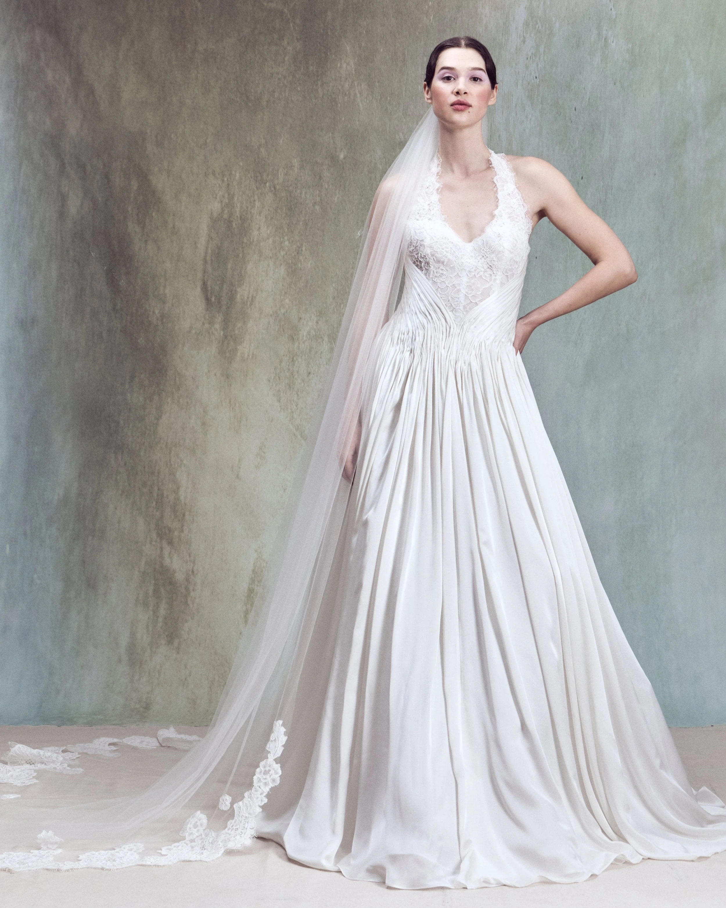 Corded lace applique gown with V-neckline halter bustier and hand-draped silk satin chiffon detail wrapping around the waist. 