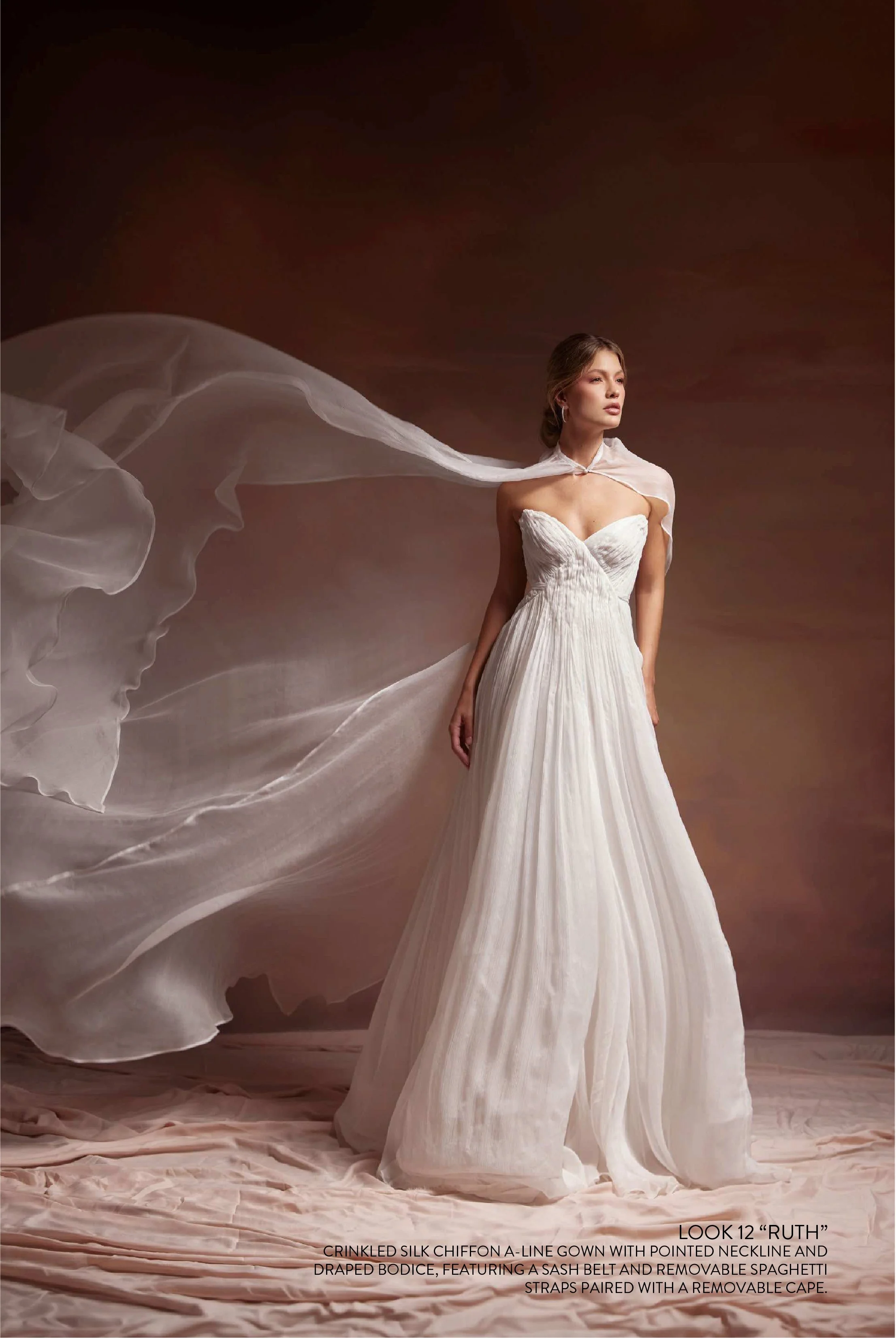 RUTH GOWN - Crinkled silk chiffon A line gown with pointed neckline and draped bodice, featuring a sash belt and removable spaghetti straps paired with silk chiffon cape.