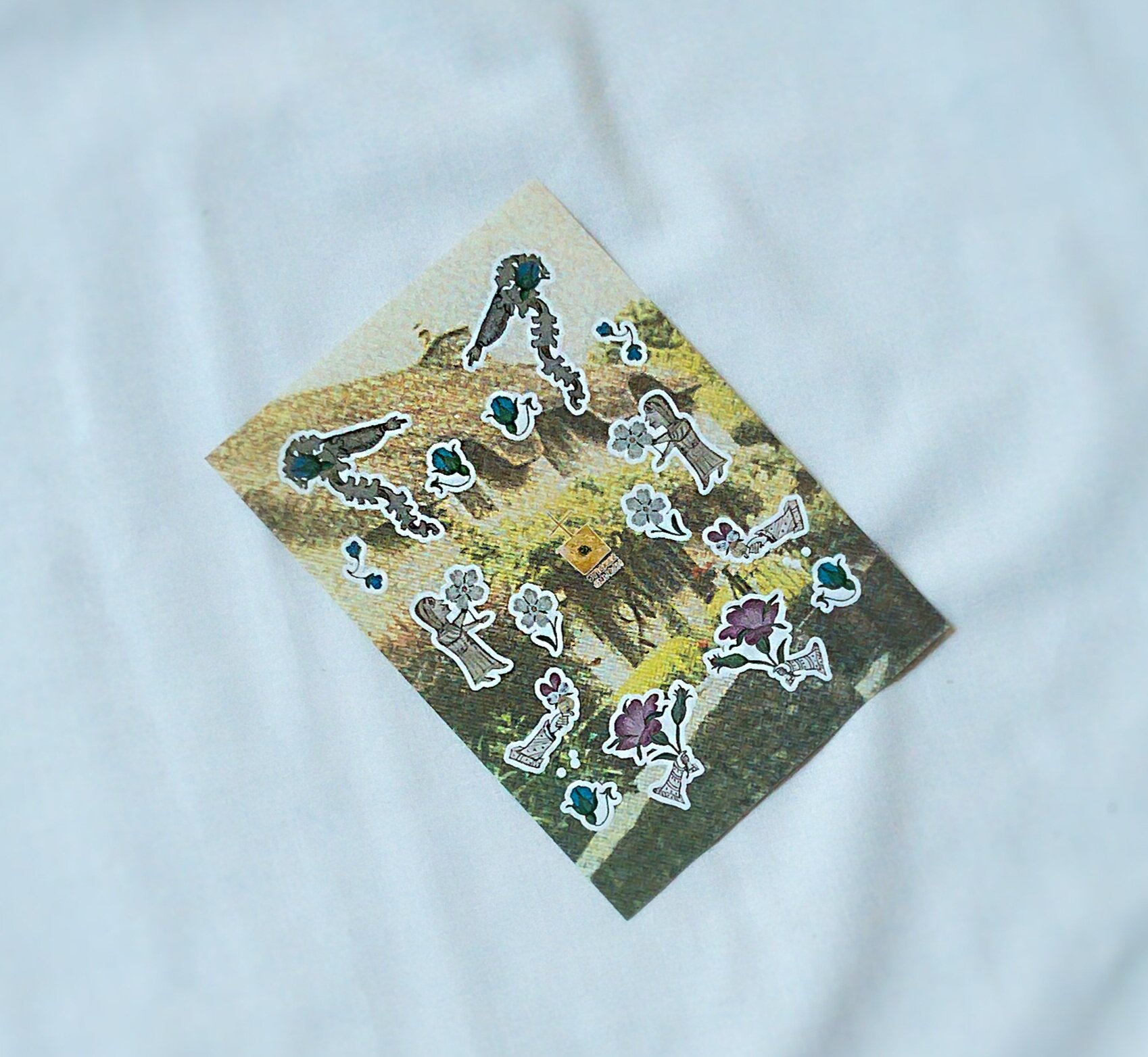 Sticker sheet with designs of medieval manicules featuring flowers, plant tendrils and human figures, in front of a neutral background.