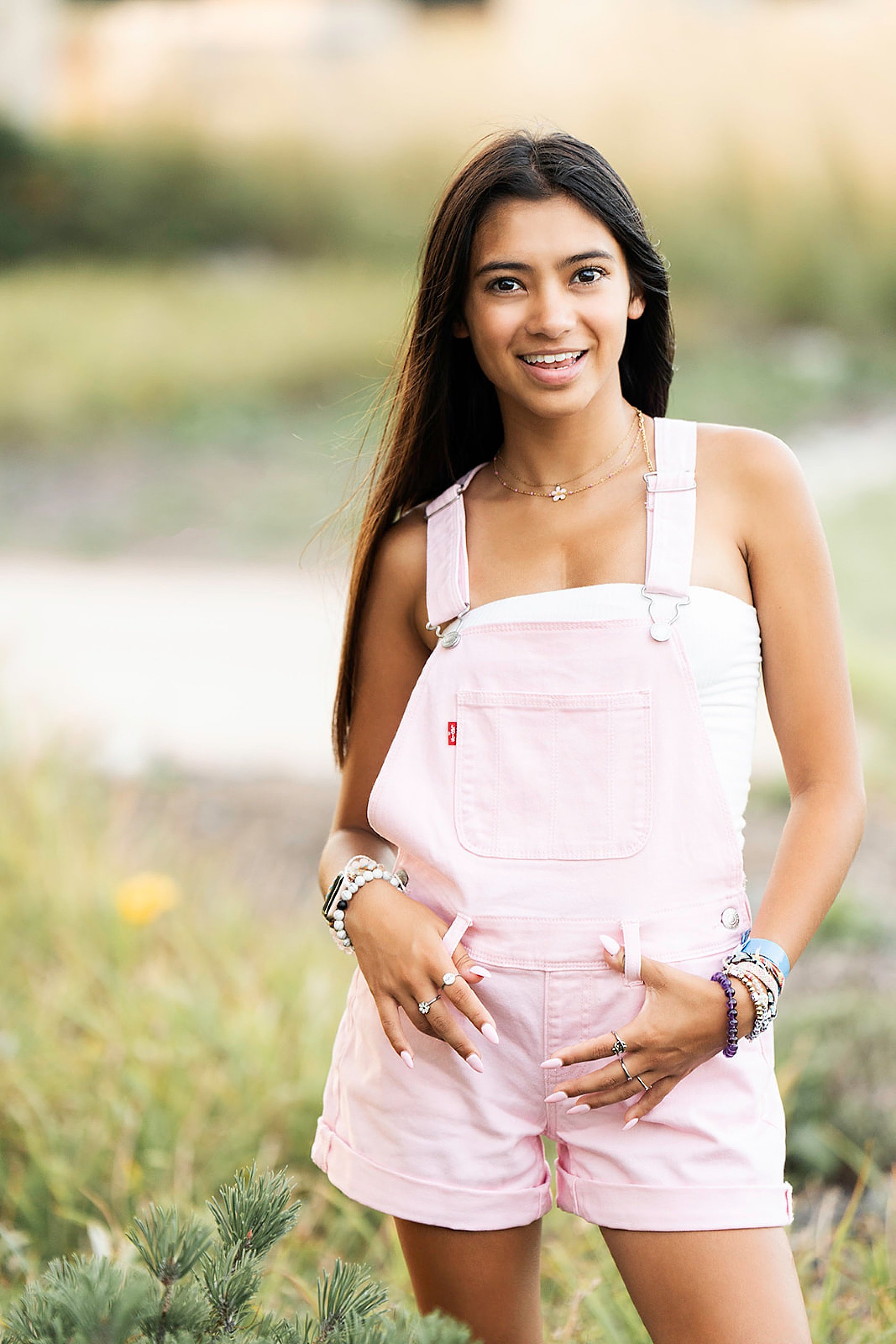  Senior girl in pink overalls in open field of Kansas City  