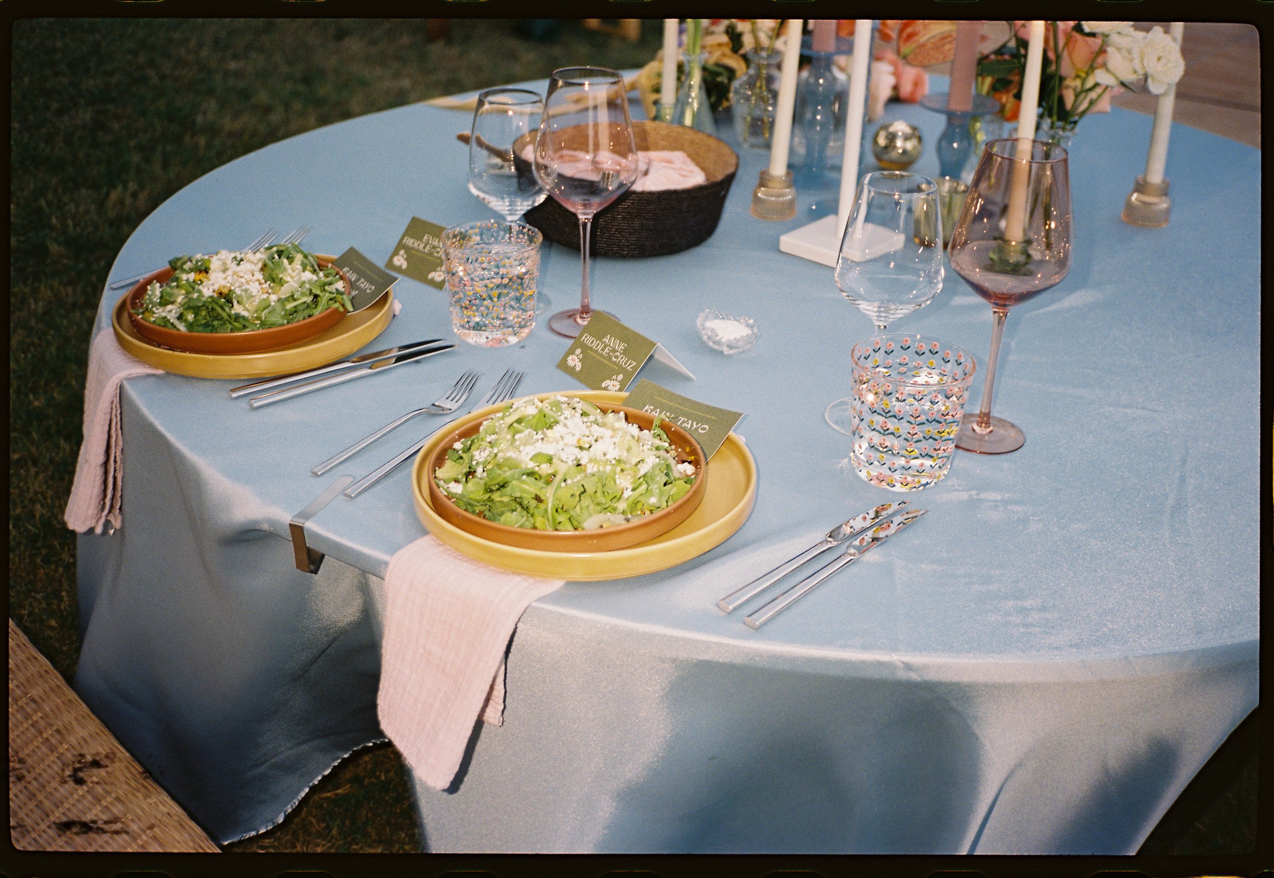 A table set for a meal with two salads, wine glasses, water glasses, and decorative centerpieces.