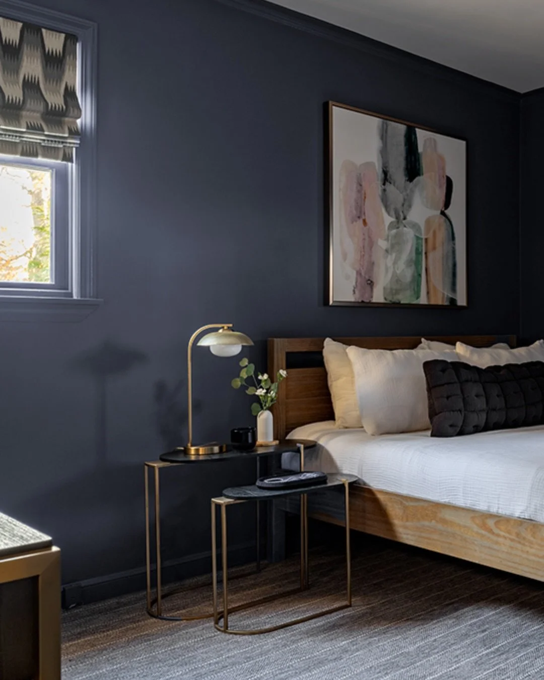 Welcoming guests this holiday season? One of our favorite guest rooms is designed to impress.

Color-drenched walls, oval nesting tables that double as a nightstand, patterned Roman shades and a soft gray-striped carpet come together to create the pe