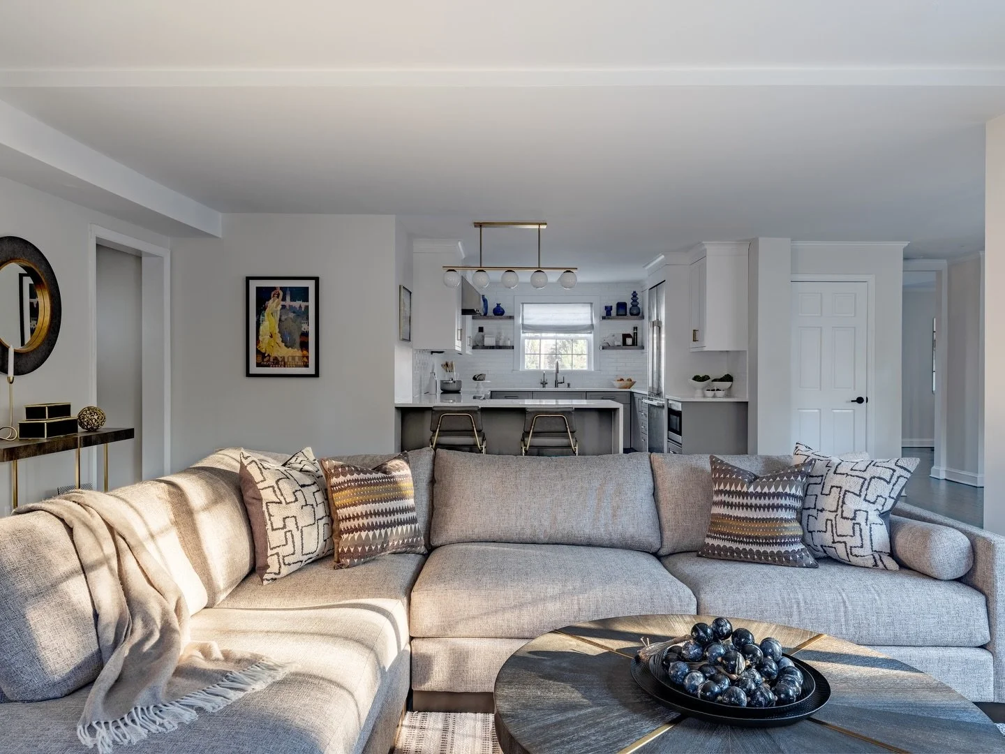 To make sure the kitchen and family room relate to each other in this open concept space, we used layers of color that create an ombre effect with deep grey tones fading into white. 

Gray leads in the sectional and lower cabinetry, with earth tones 
