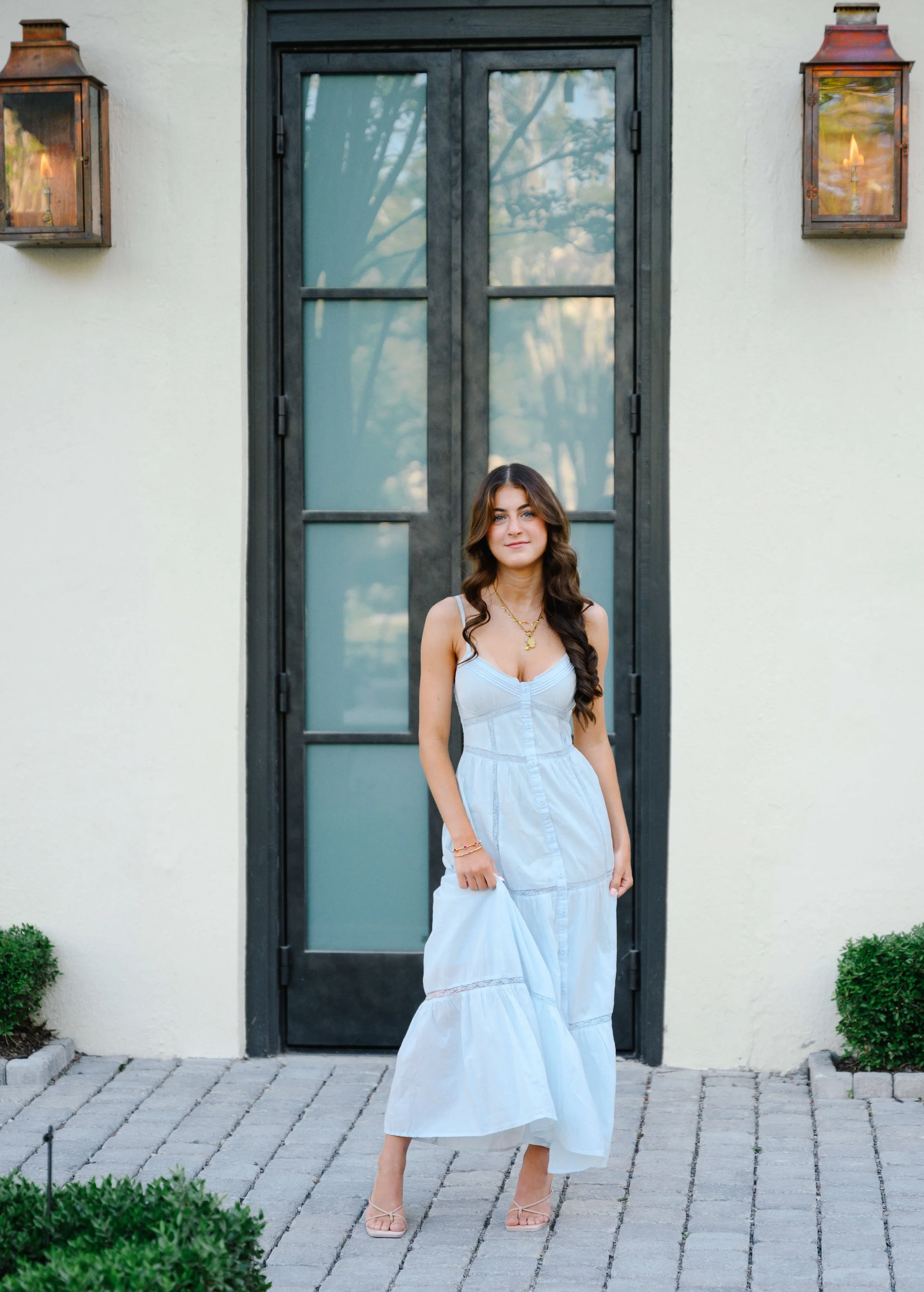 Charleston senior portrait framed by dark French doors and iron lanterns American Gardens King Street