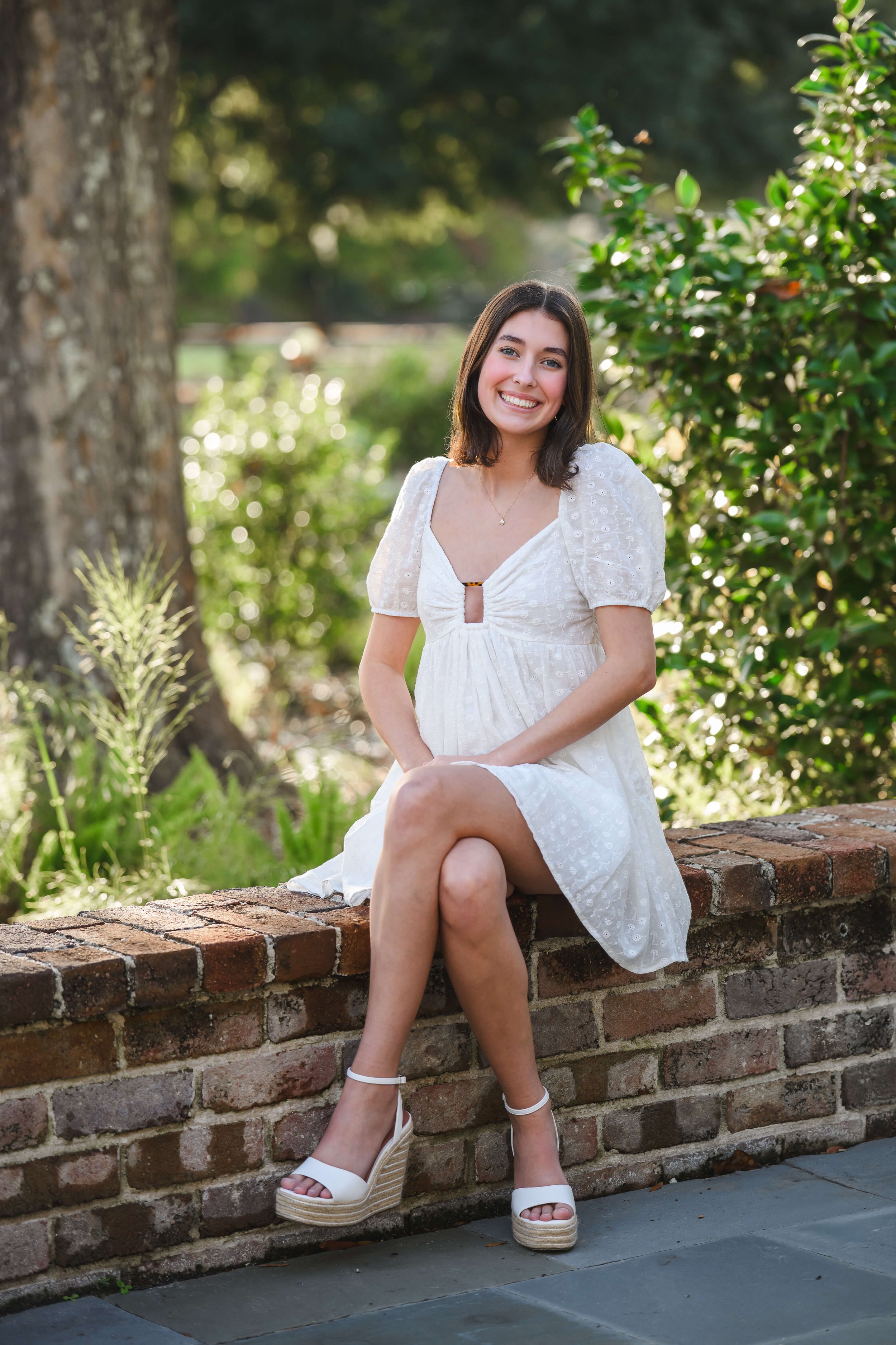 Girl sitting on brick wall at Hampton Park for Senior Photos