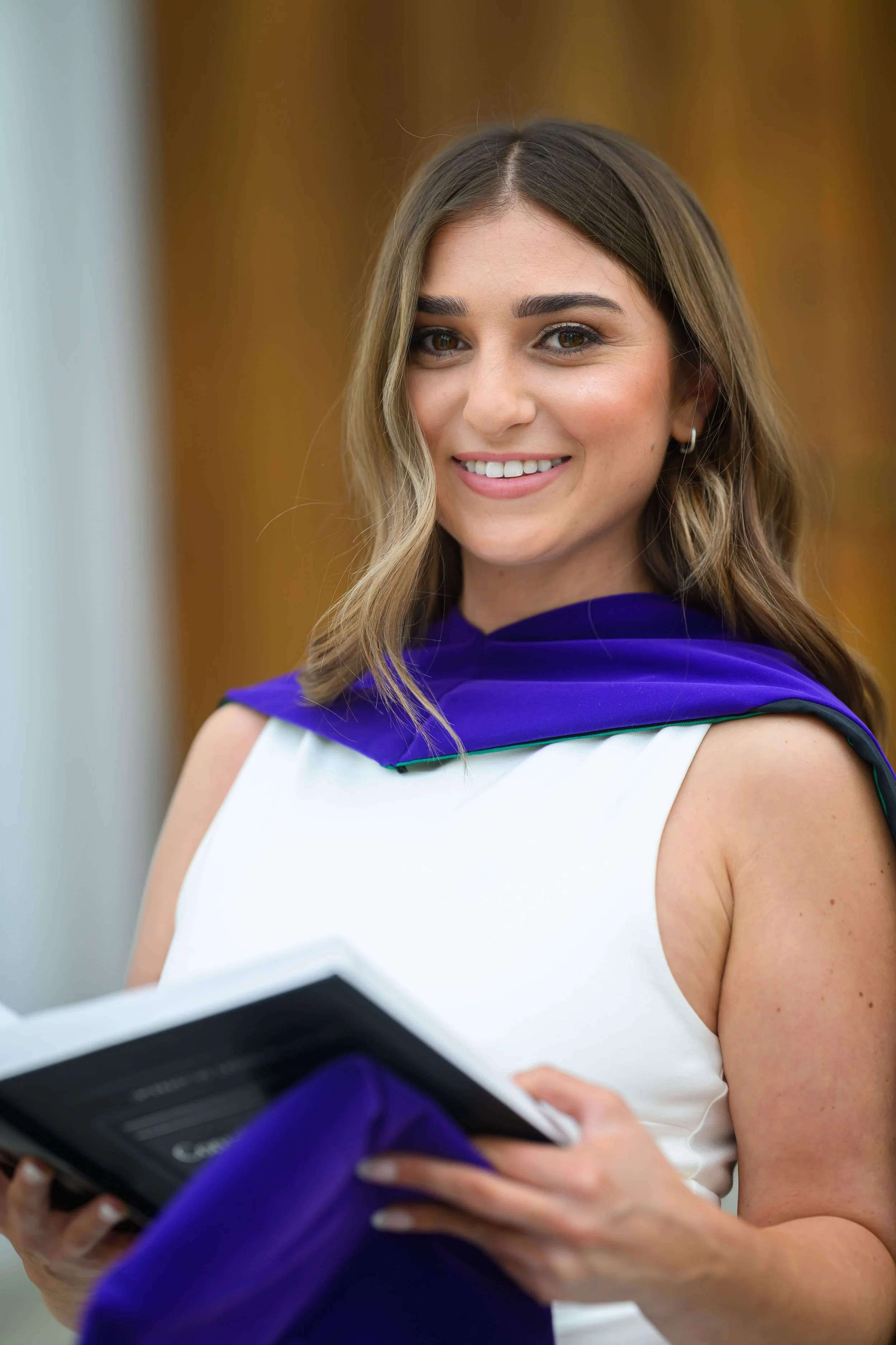 Charleston School of Law Grad Student holding law book wearing a white dress and hood