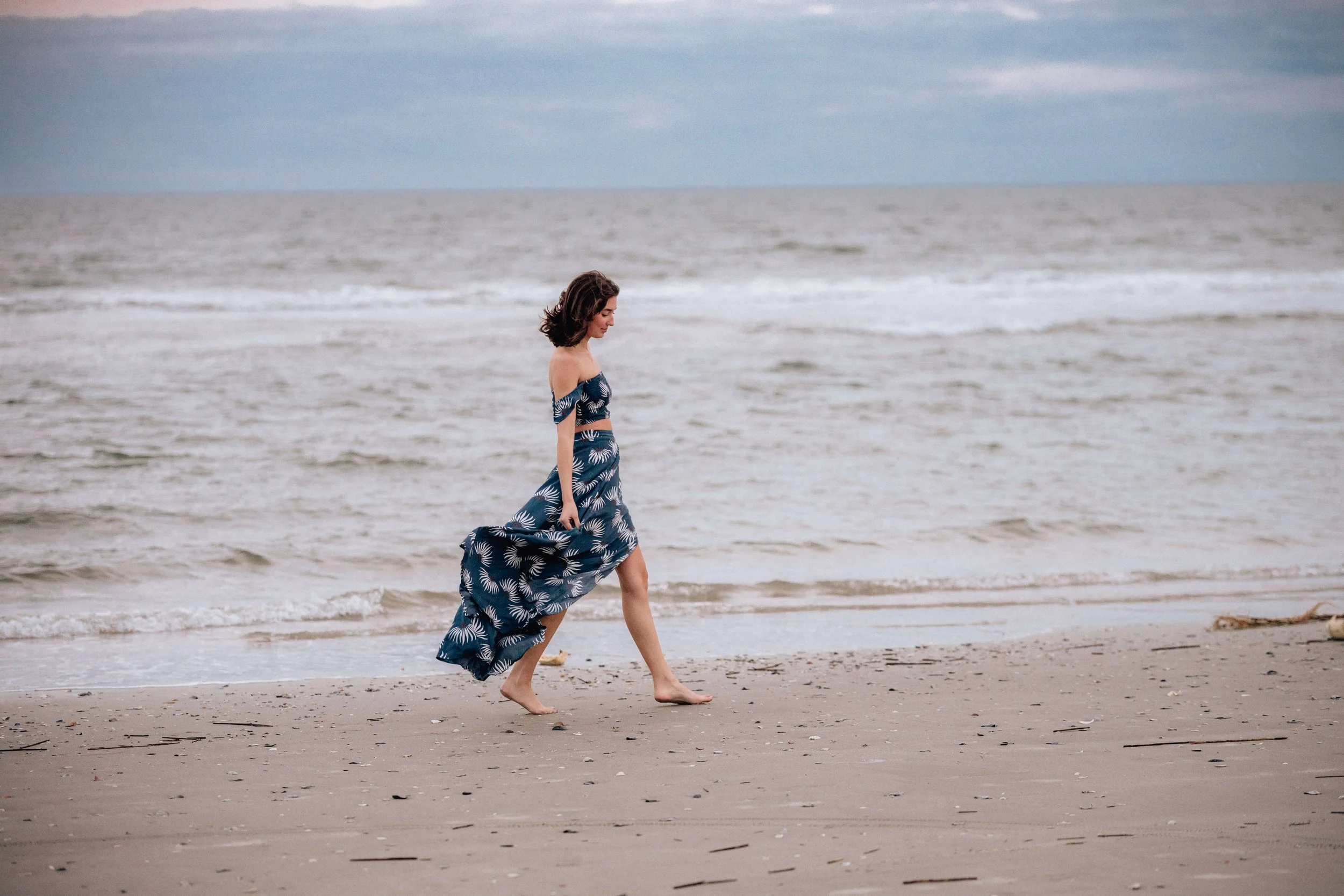 Girl walking along the shore at sunset at Isle of Palms Beach.