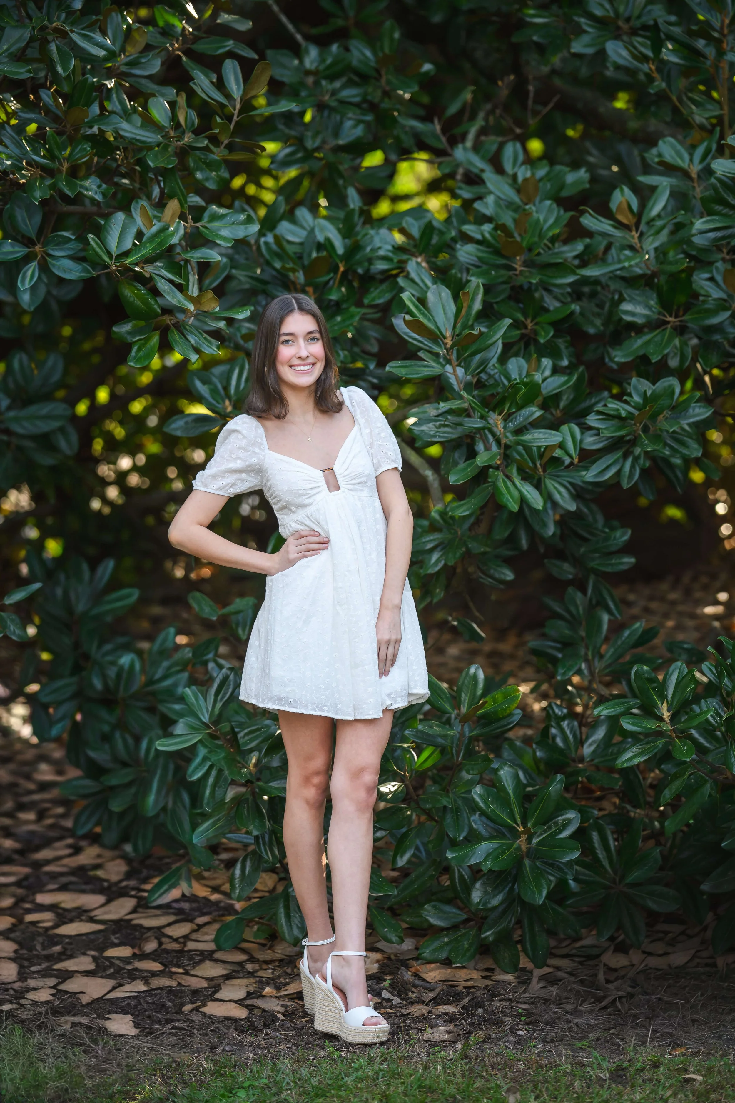 full length photo of girl with large magnolia bush in Hampton Park, Charleston SC for senior photos