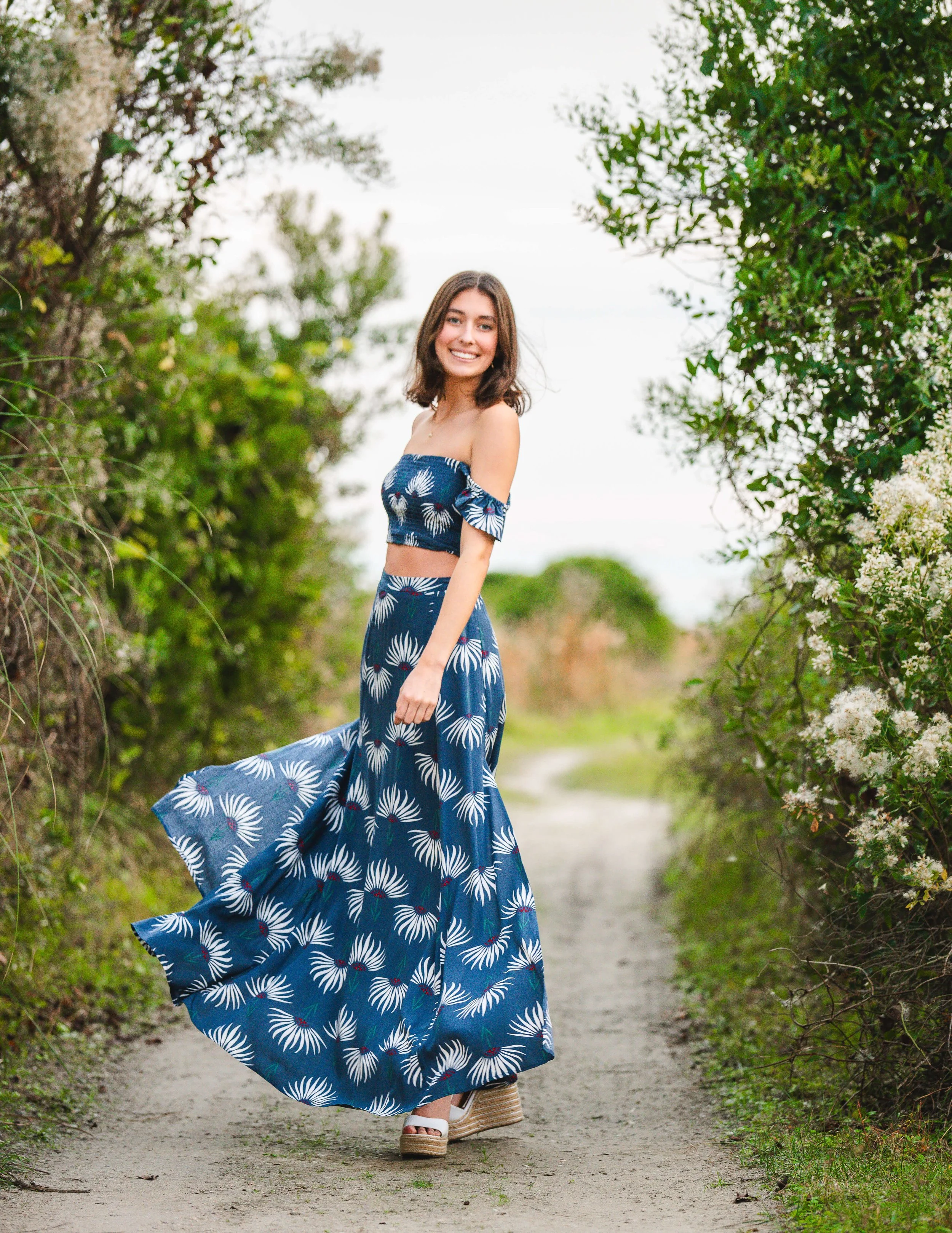 girl with flowy skirt playful pose at IOP beach path in SC for senior photos