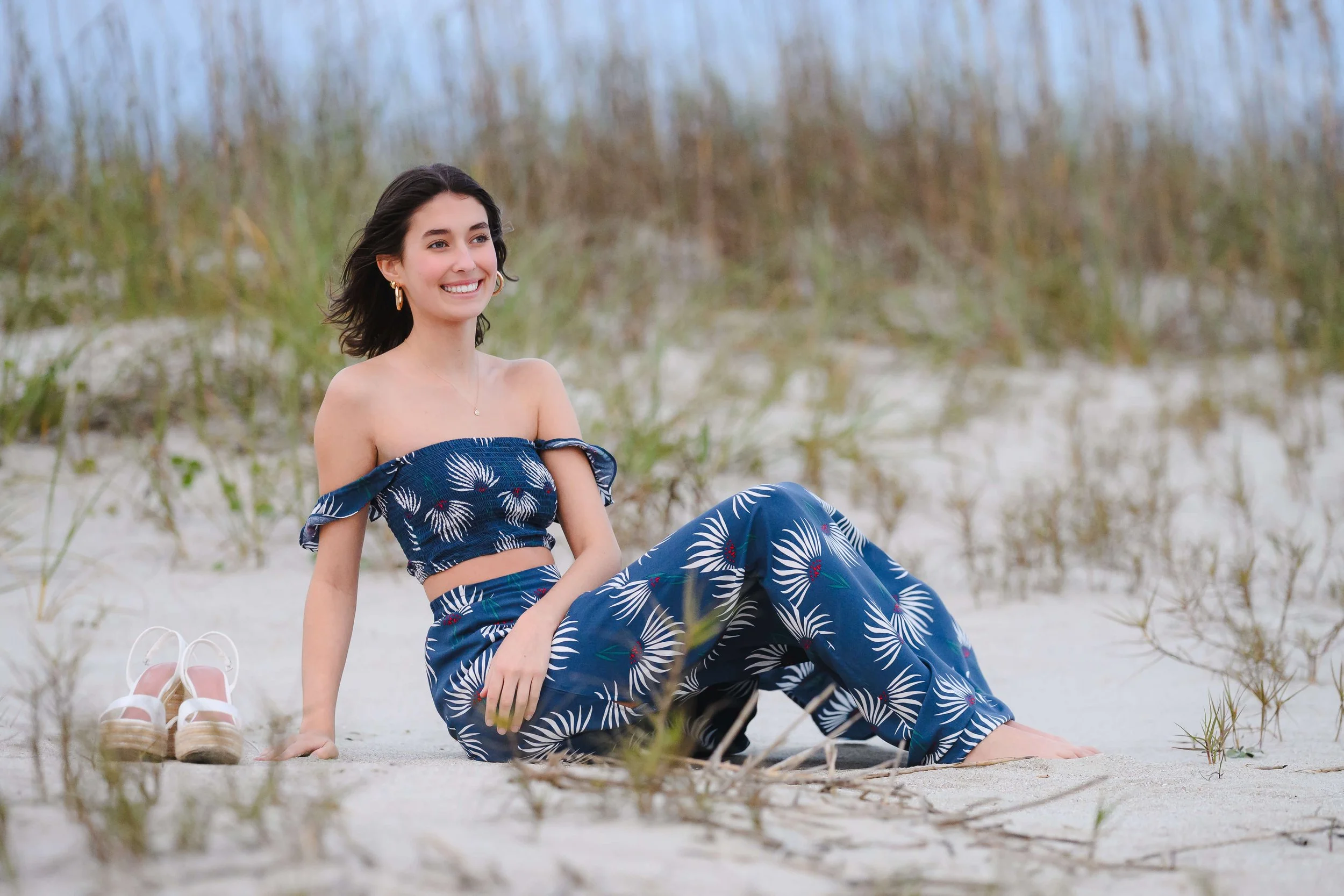 Girl sitting by dunes at Isle of Palms beach for senior photos.