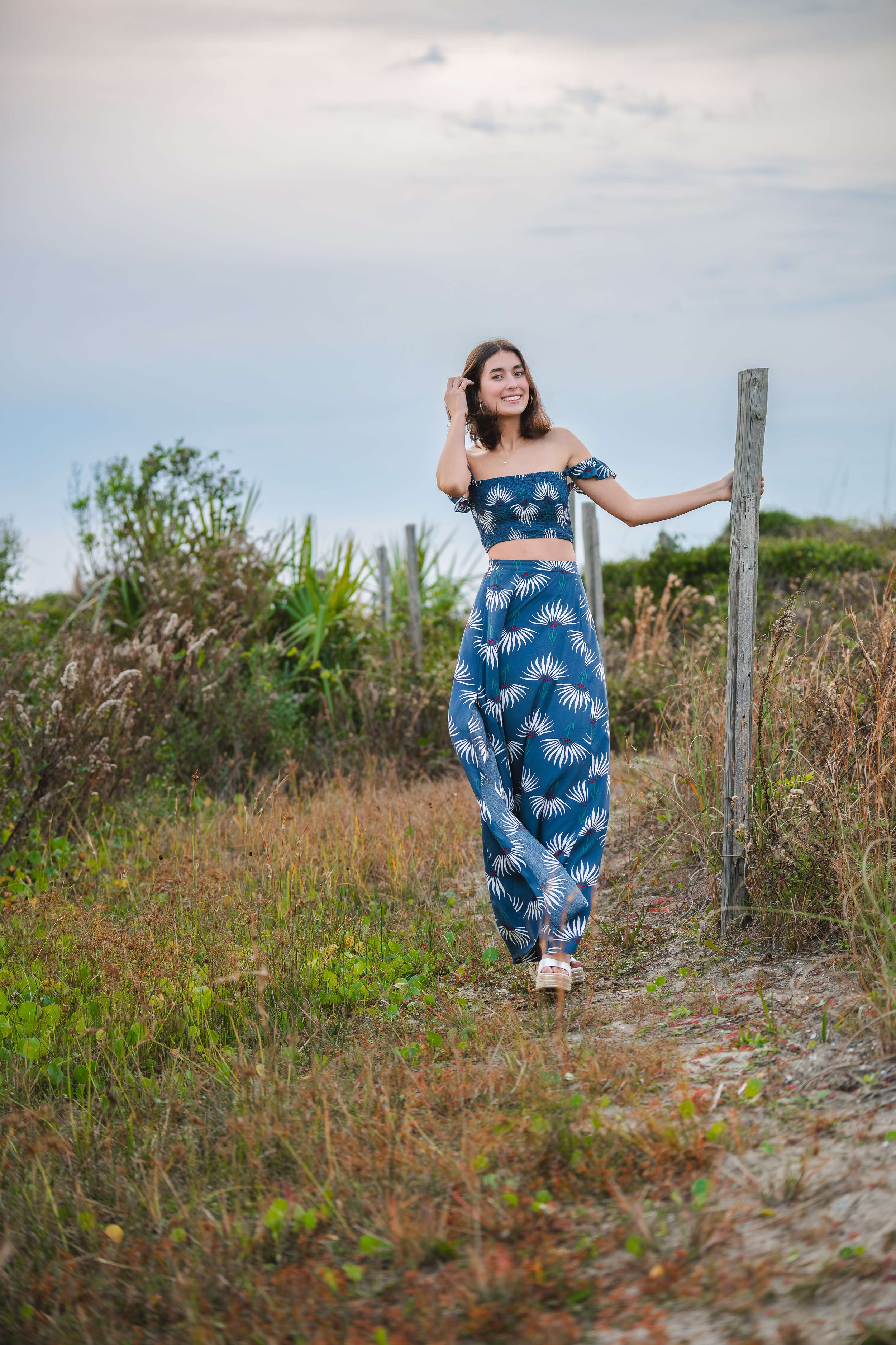 Girl posing for senior photos on field at Isle of Palms Beach.