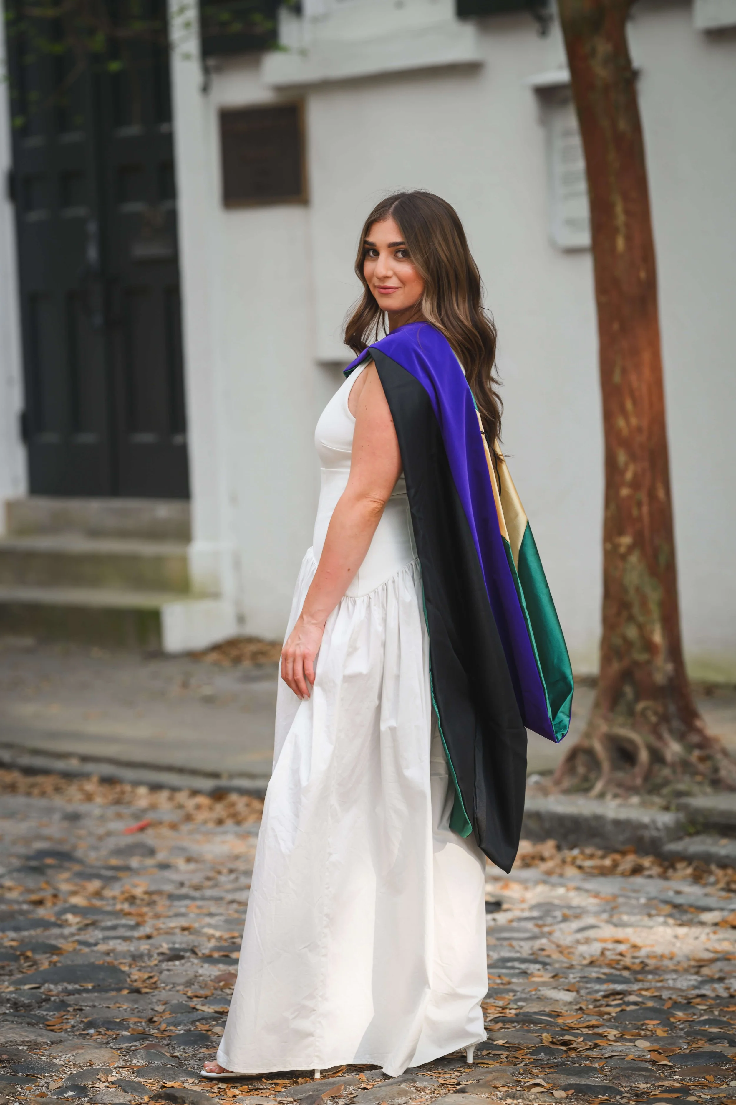 young woman wearing Charleston School of Law graduation hood and posing on Chalmers St.