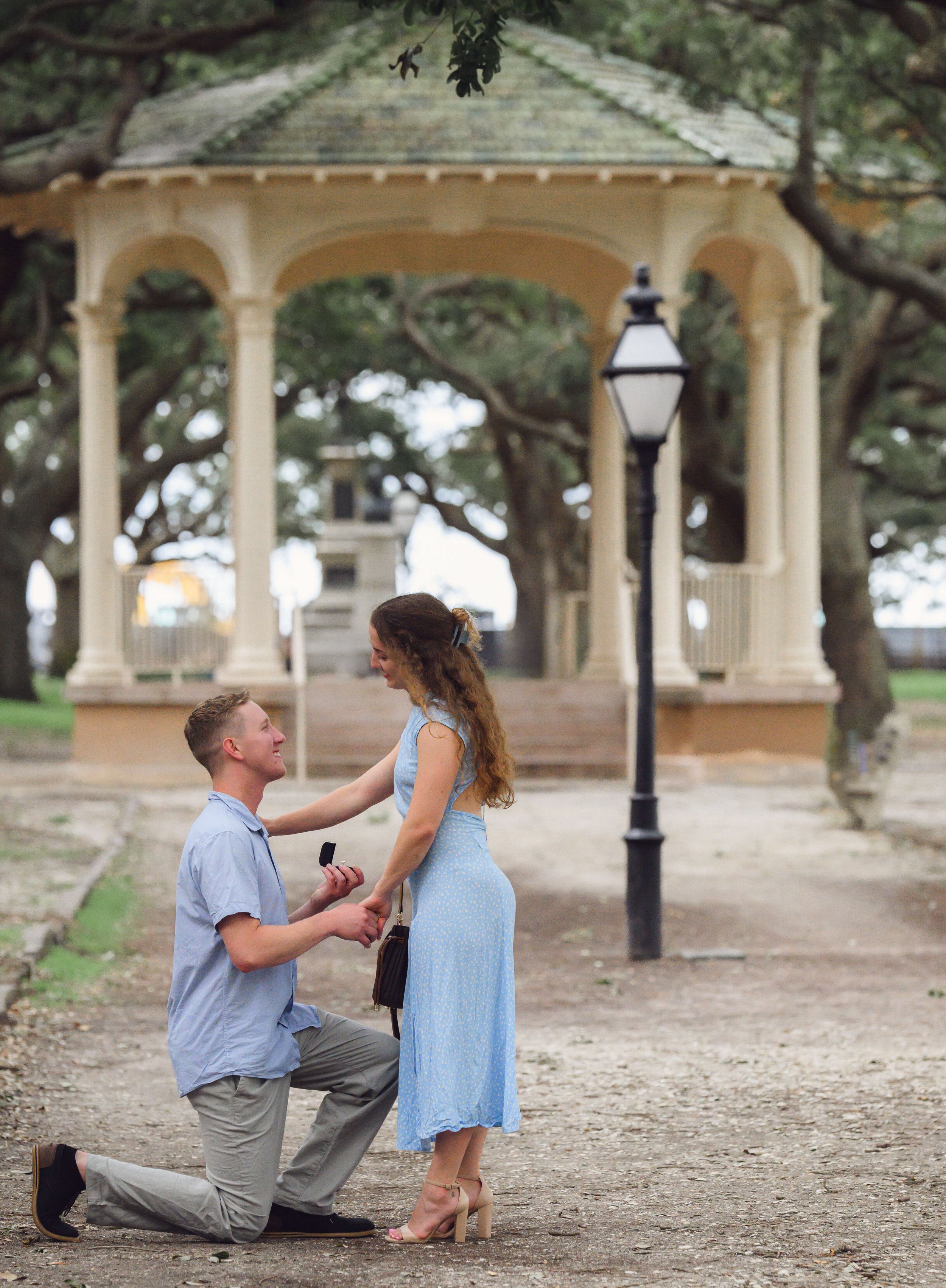 A man in a blue top proposes to his new fiancé at White Point Gardens in Charleston, SC