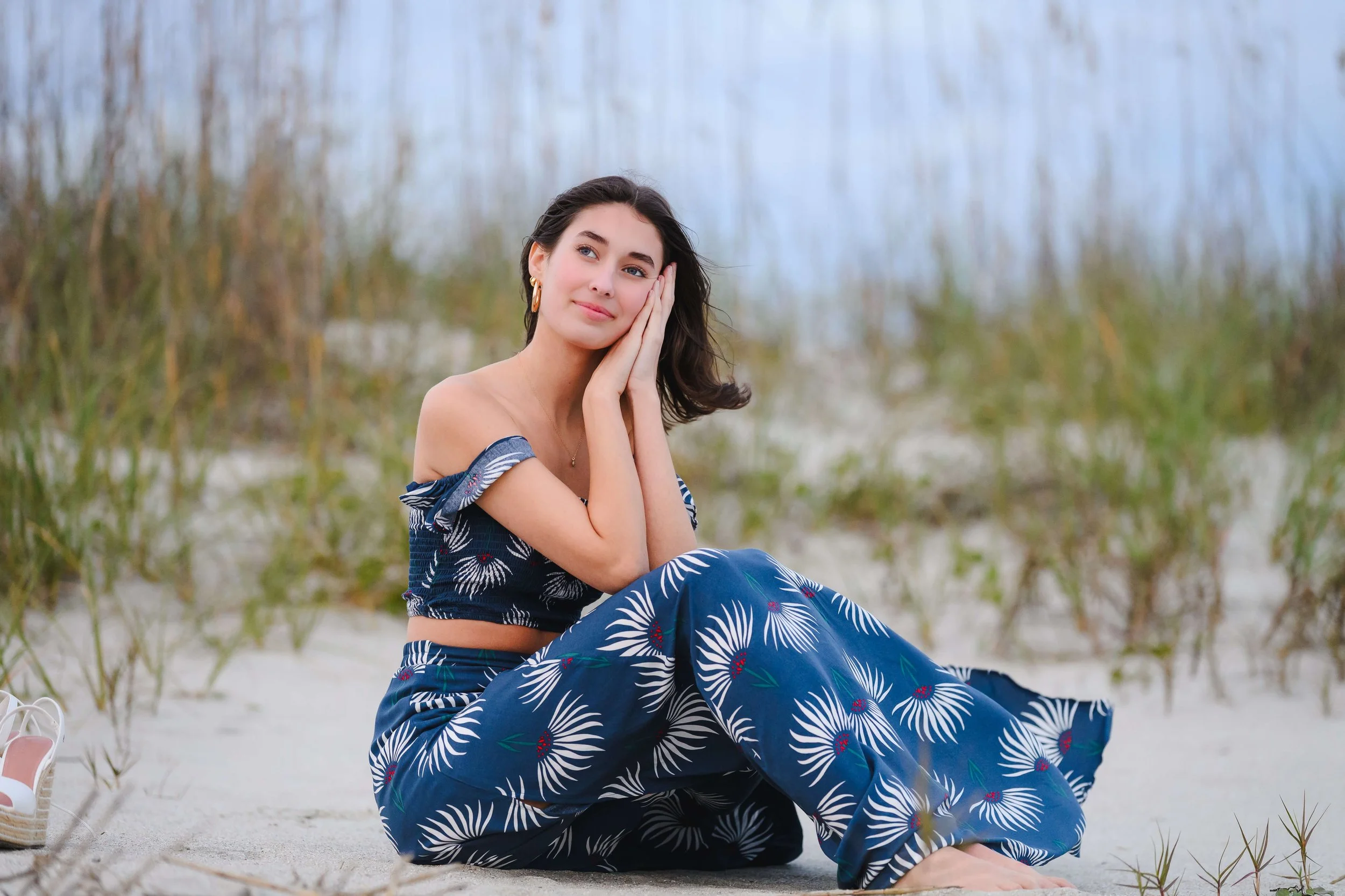 Girl with gentle smile sitting by dunes at Isle of Palms beach. 