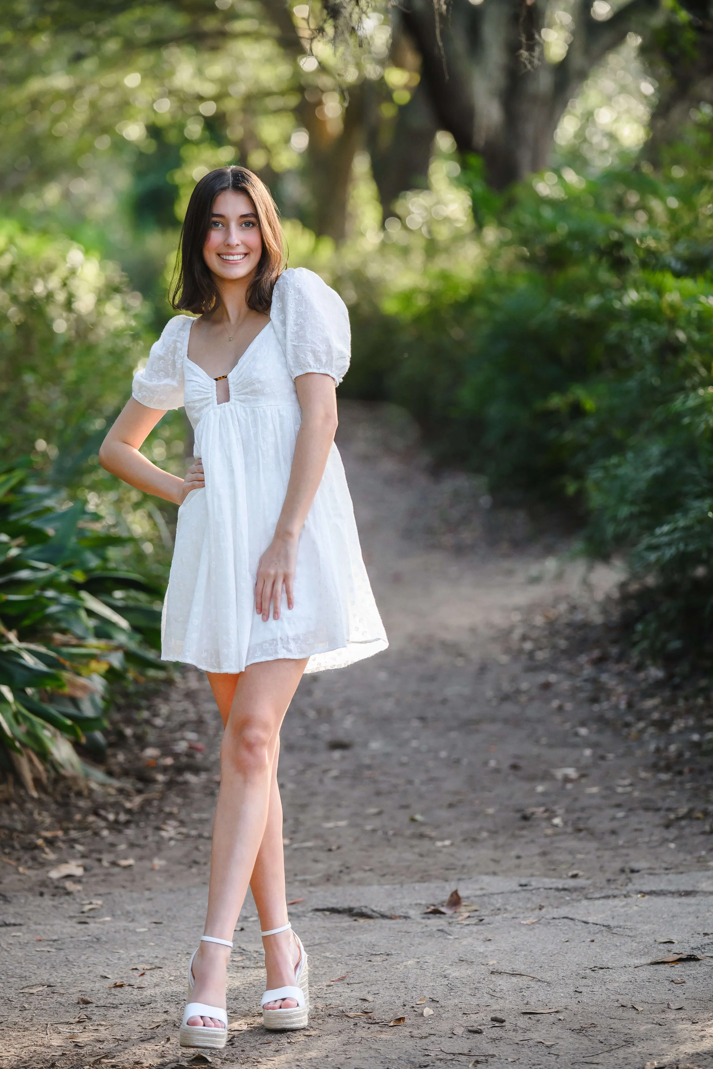girl with and on hip posing for senior photos at Hampton Park in Charleston