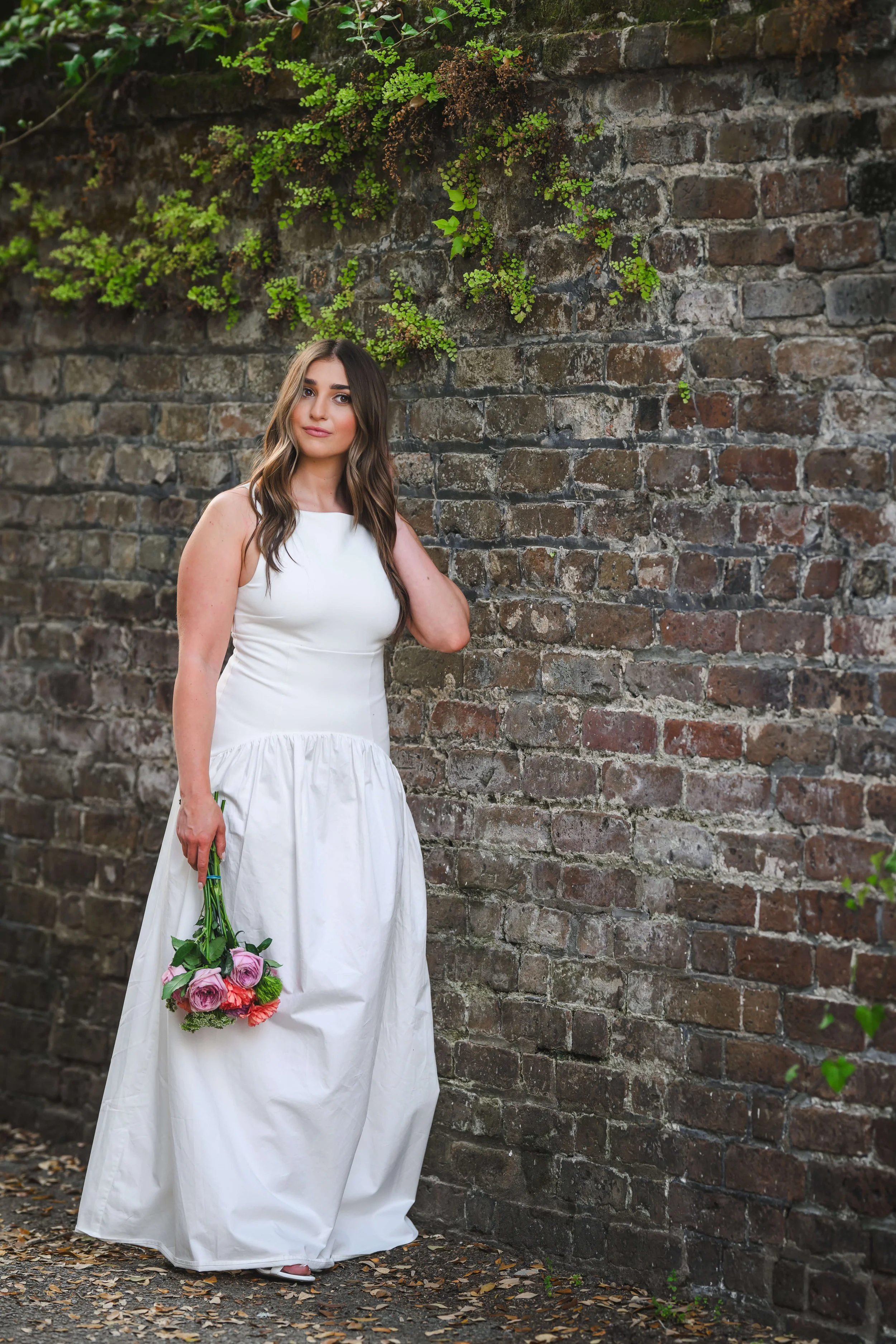 Charleston School of Law Grad Student in white dress hold bouquet of flowers