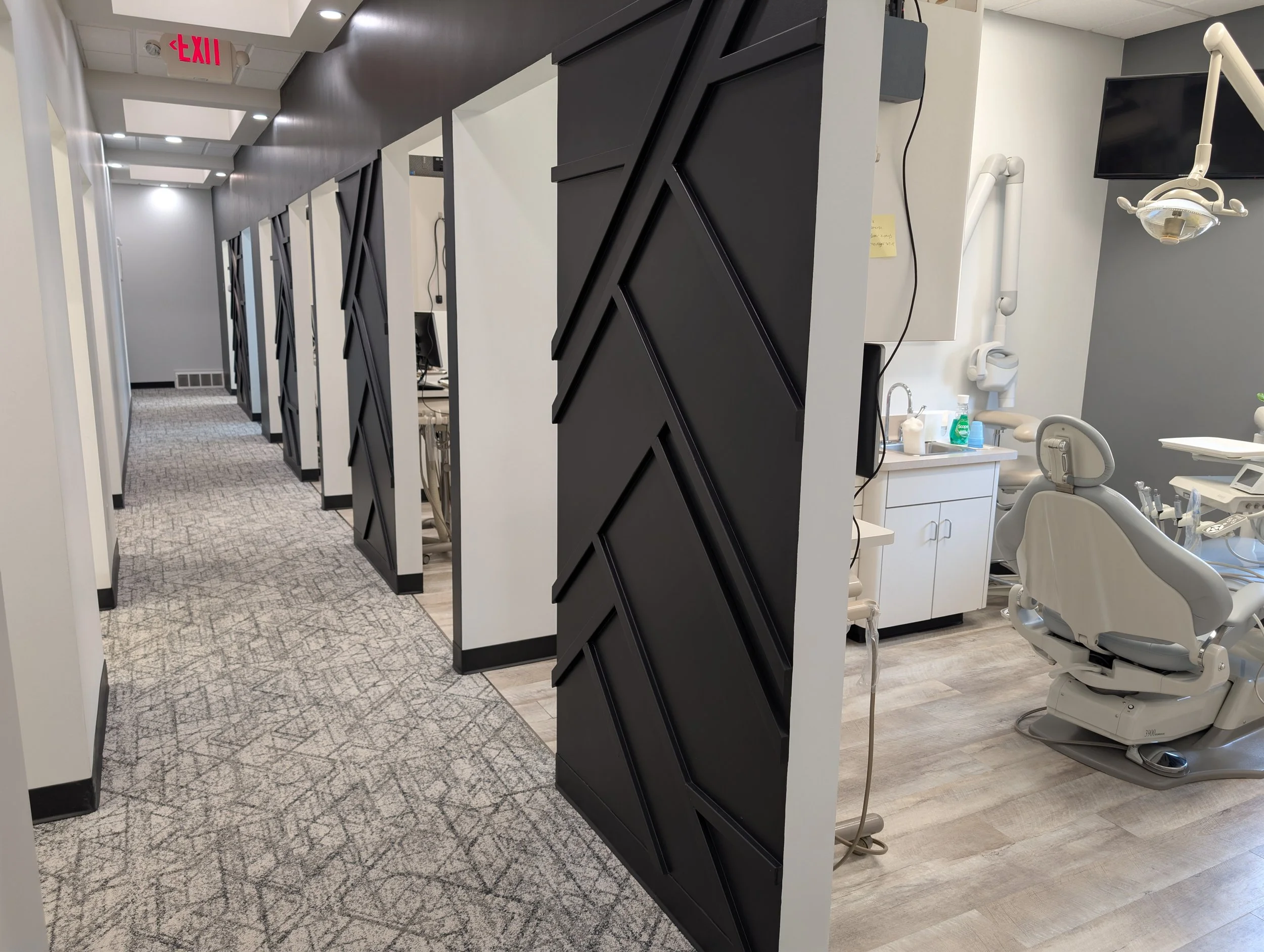 Hallway with treatment rooms and a dental office on the right, featuring dental chair, dental equipment, and a cabinet.