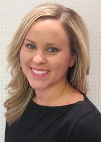 A smiling woman with blonde hair and wearing a black top.