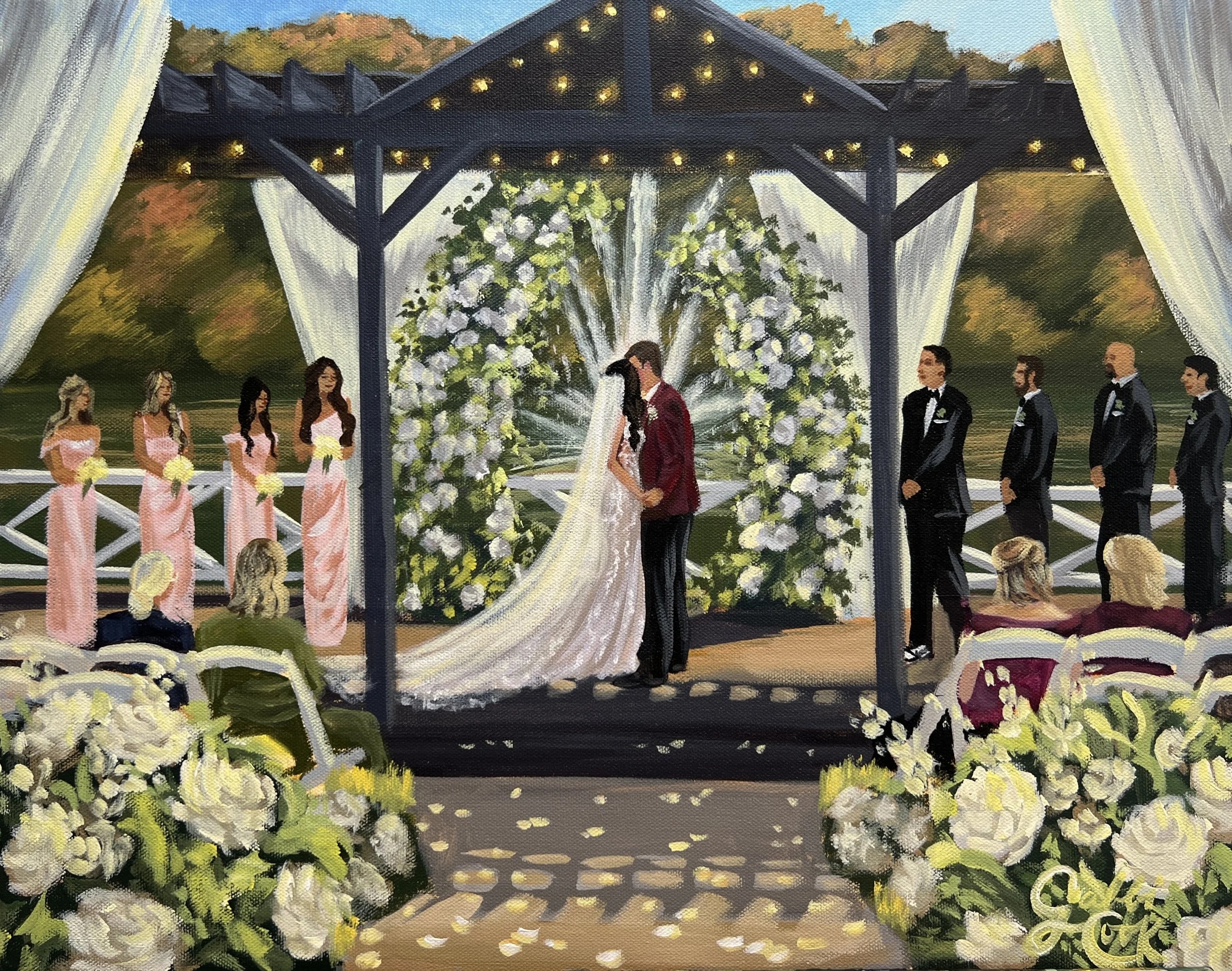 A wedding ceremony taking place outdoors on a stage decorated with white flowers and drapery, with a bride and groom kissing under an arch, surrounded by bridesmaids in pink dresses on the left and groomsmen in black tuxedos on the right, with guests