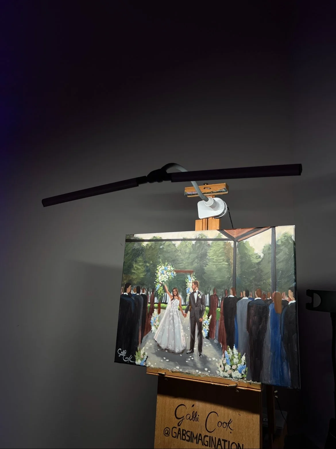 Painting of a wedding scene with a bride and groom holding hands, surrounded by guests in formal attire, outdoors with trees and floral decorations.