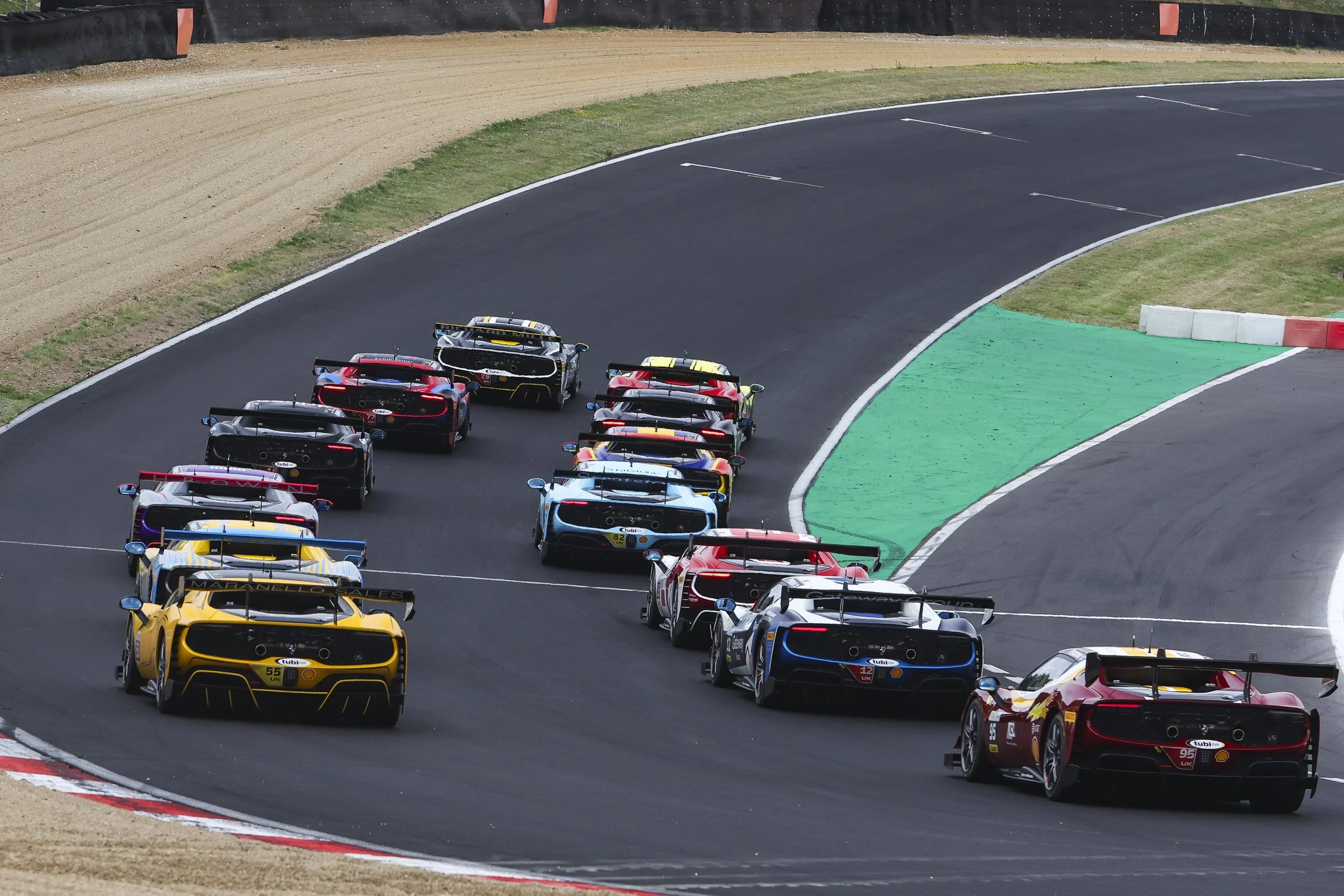 A group of race cars speeding around a curved racetrack during a race.