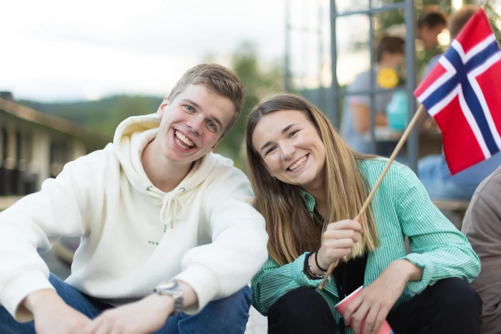 To smilende elever med norsk flagg