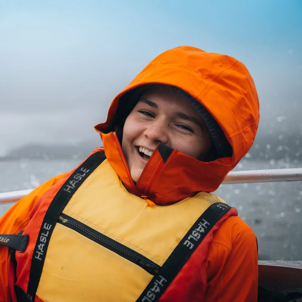 Smilende elev i oransje jakke