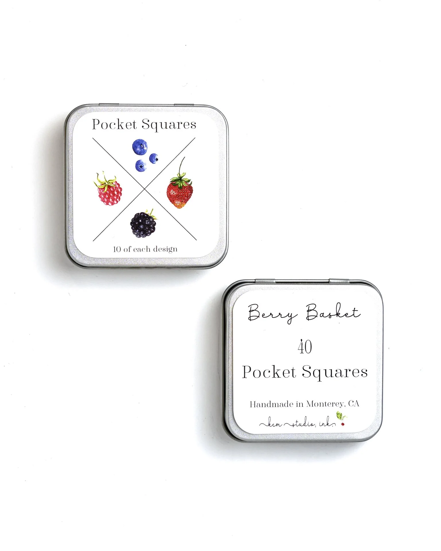 Two small tins of berry-flavored pocket squares with handwritten labels, one with images of various berries and the other with text 'Berry Basket' and details about handmade in Monterey, CA.