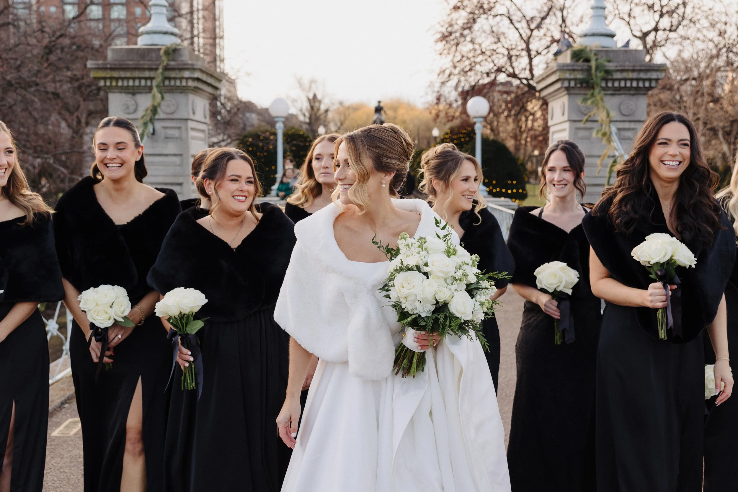 Bride and her bridesmaids walk on the bridge in the Boston Public Garden