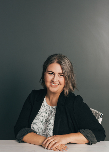 Couples therapist Detroit - headshot of therapist with short gray-brown hair smiling, wearing a floral print top and a black blazer