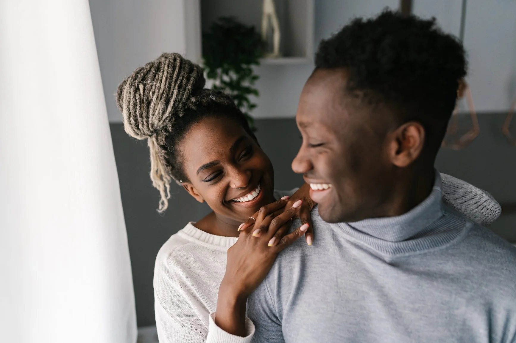 A woman and a man sharing a joyful moment, smiling and close to each other indoors. EFT Couples Therapy in Royal Oak, Michigan and online statewide