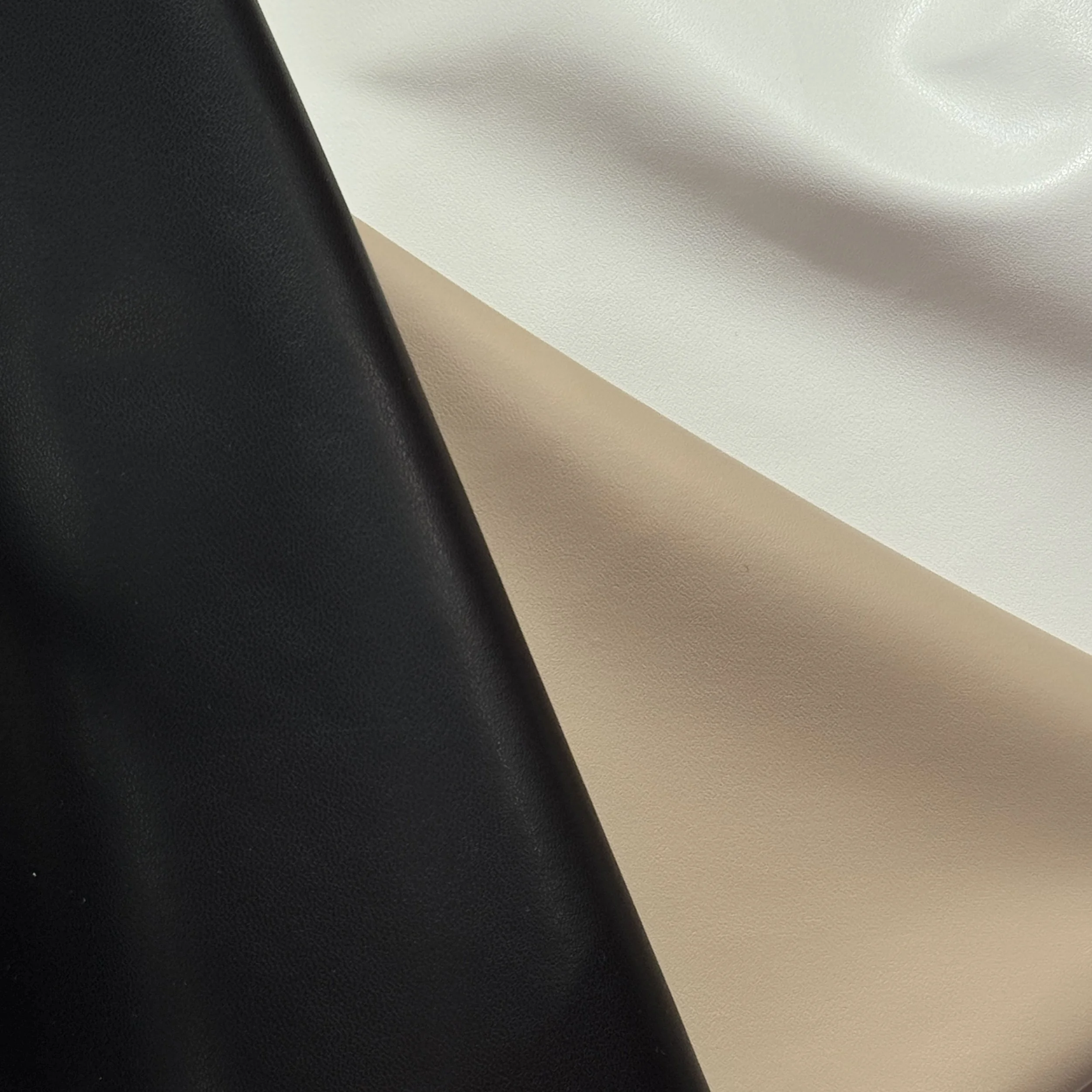 Close-up of a black leather surface next to a white textured surface with a curved shadow.