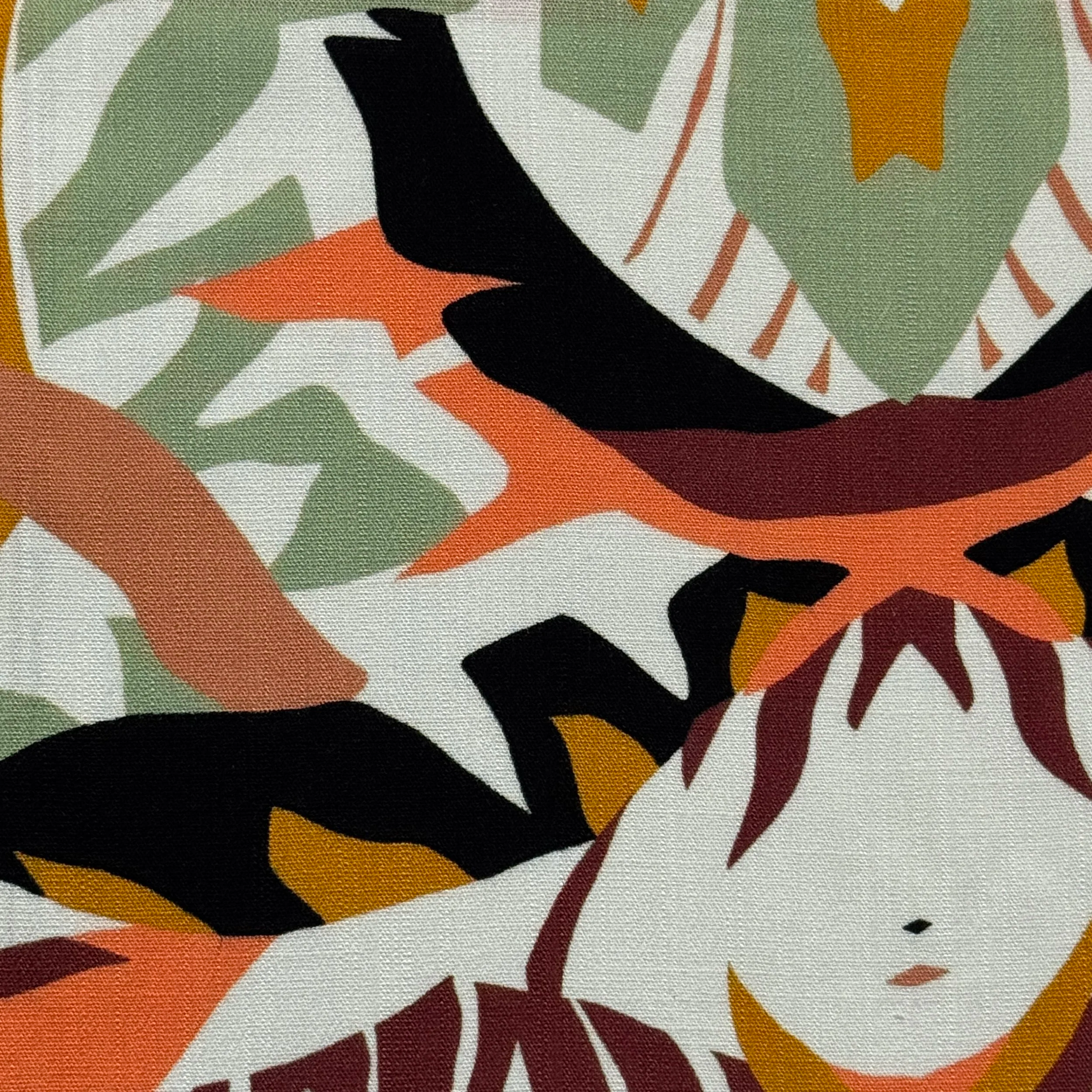 Close-up of a colorful abstract fabric with orange, green, black, white, and yellow shapes.