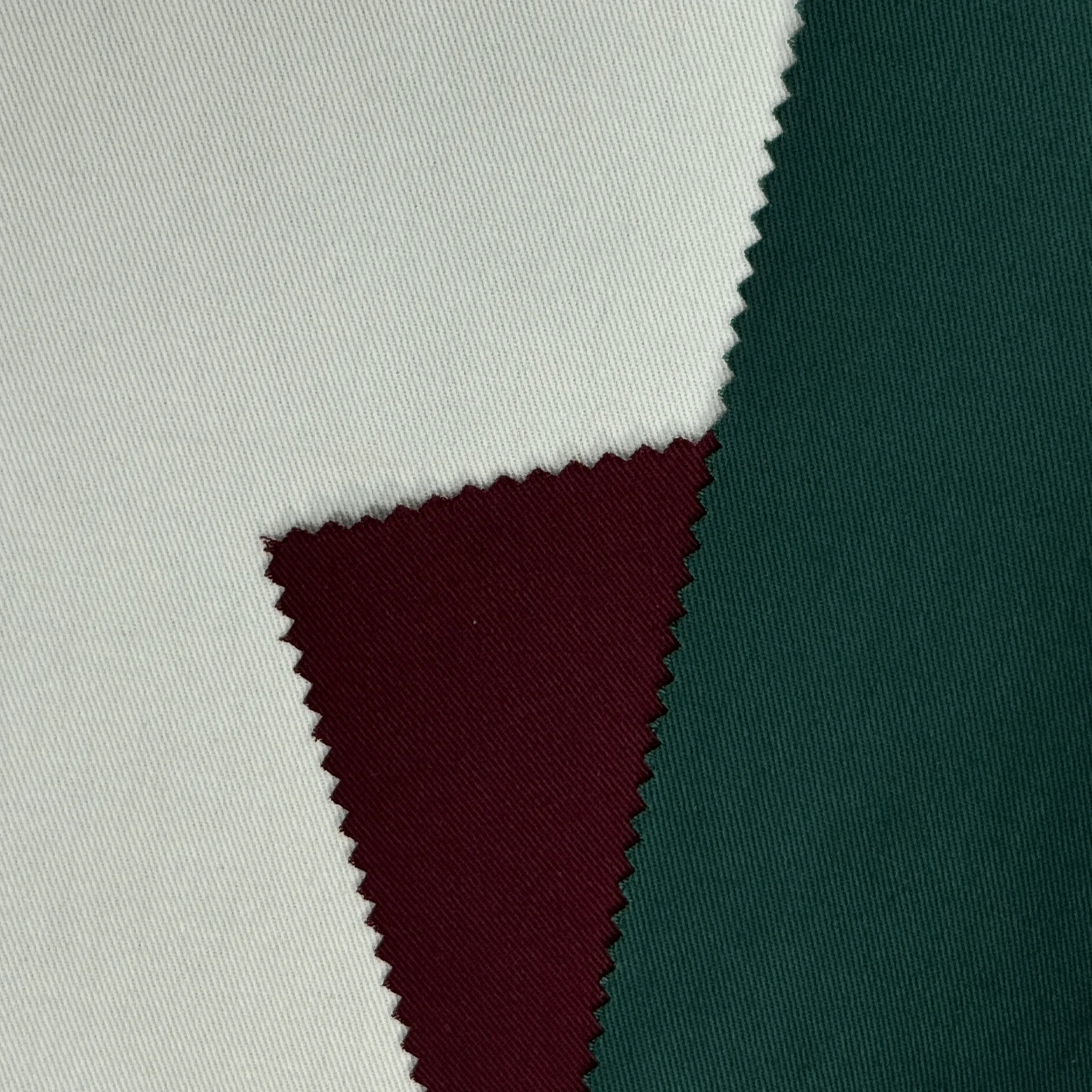 Close-up photo of woven fabric featuring the colors white, green, and red with jagged edges.