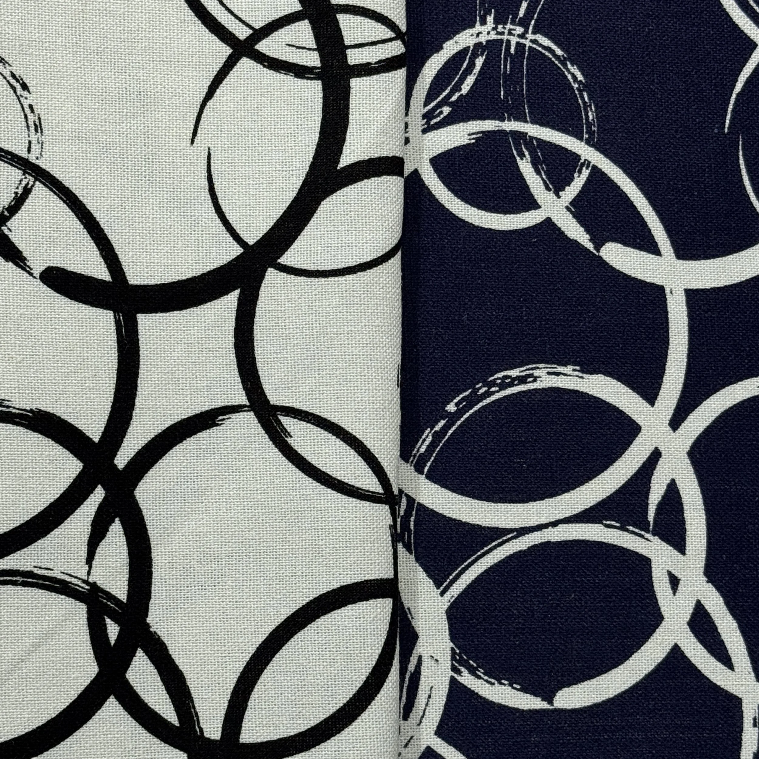 Close-up of a fabric with a black and white abstract pattern featuring circular, curved, and linear elements.