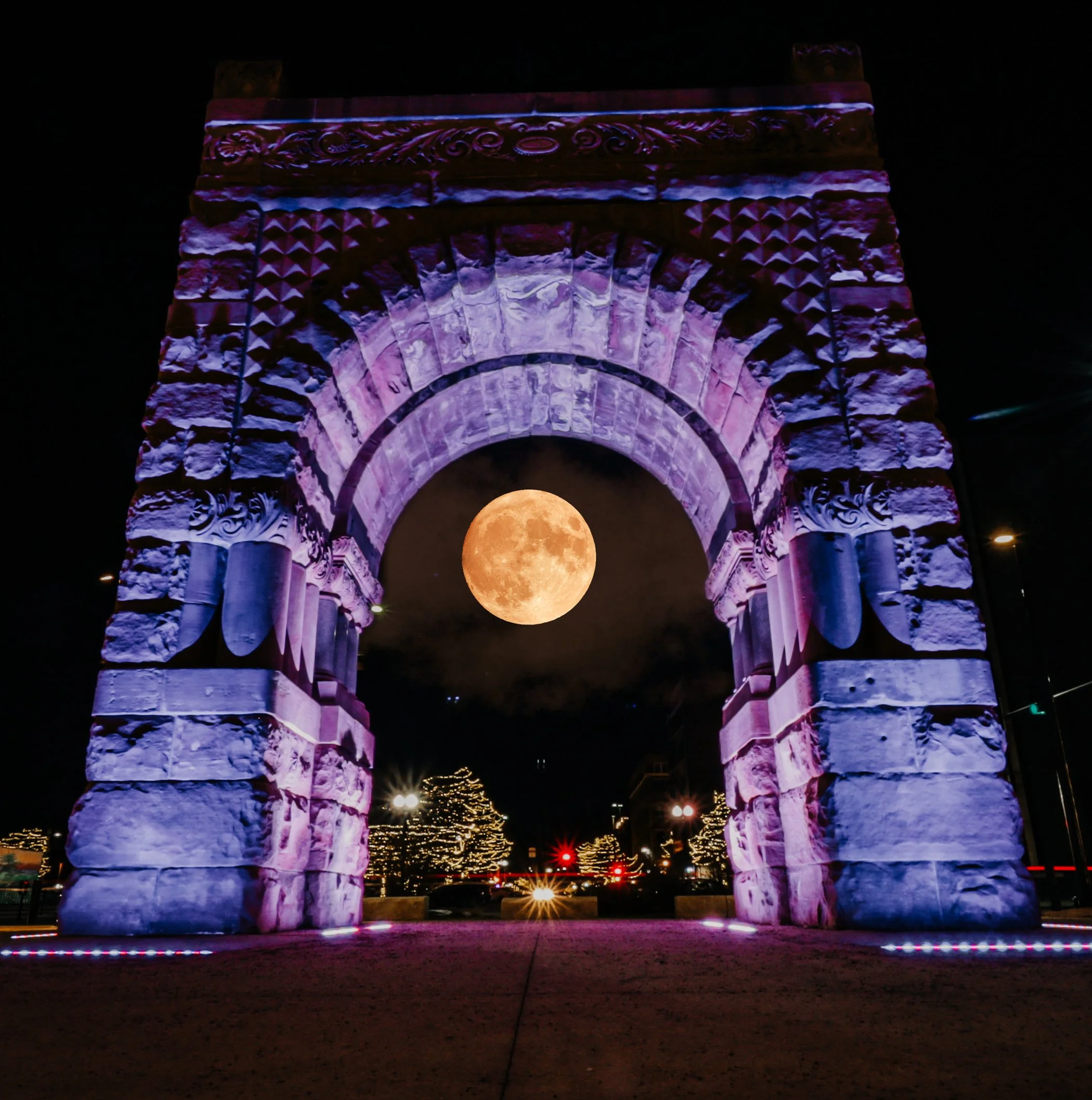 Night scene of a historic stone archway illuminated with purple and pink lights, with a large, full moon visible through the arch.