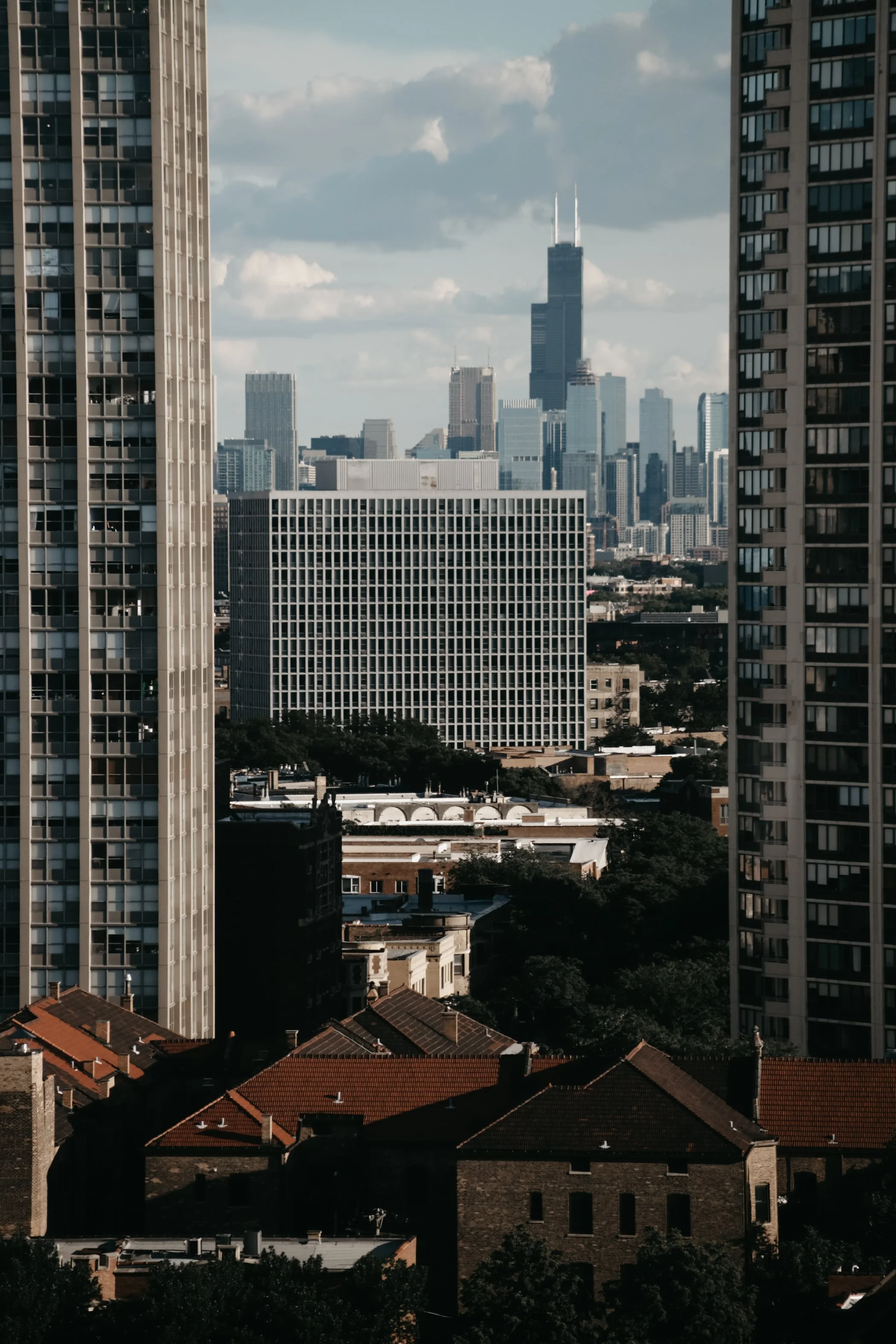 View of Chicago skyline through two tall residential buildings with red-tiled roofs in foreground.