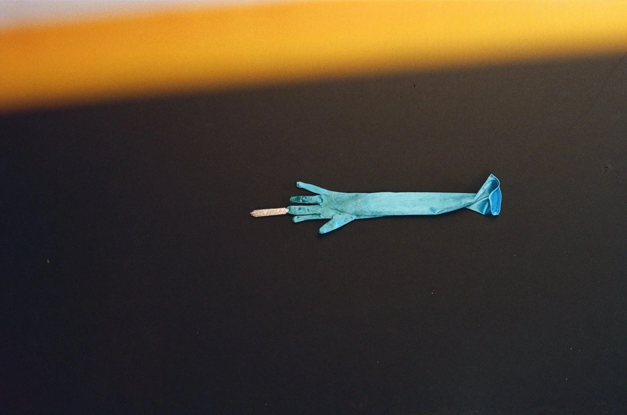 A blue latex glove holding a pair of earrings with diamond-studded, long, dangling chains, laying on a dark surface with a gradient background.